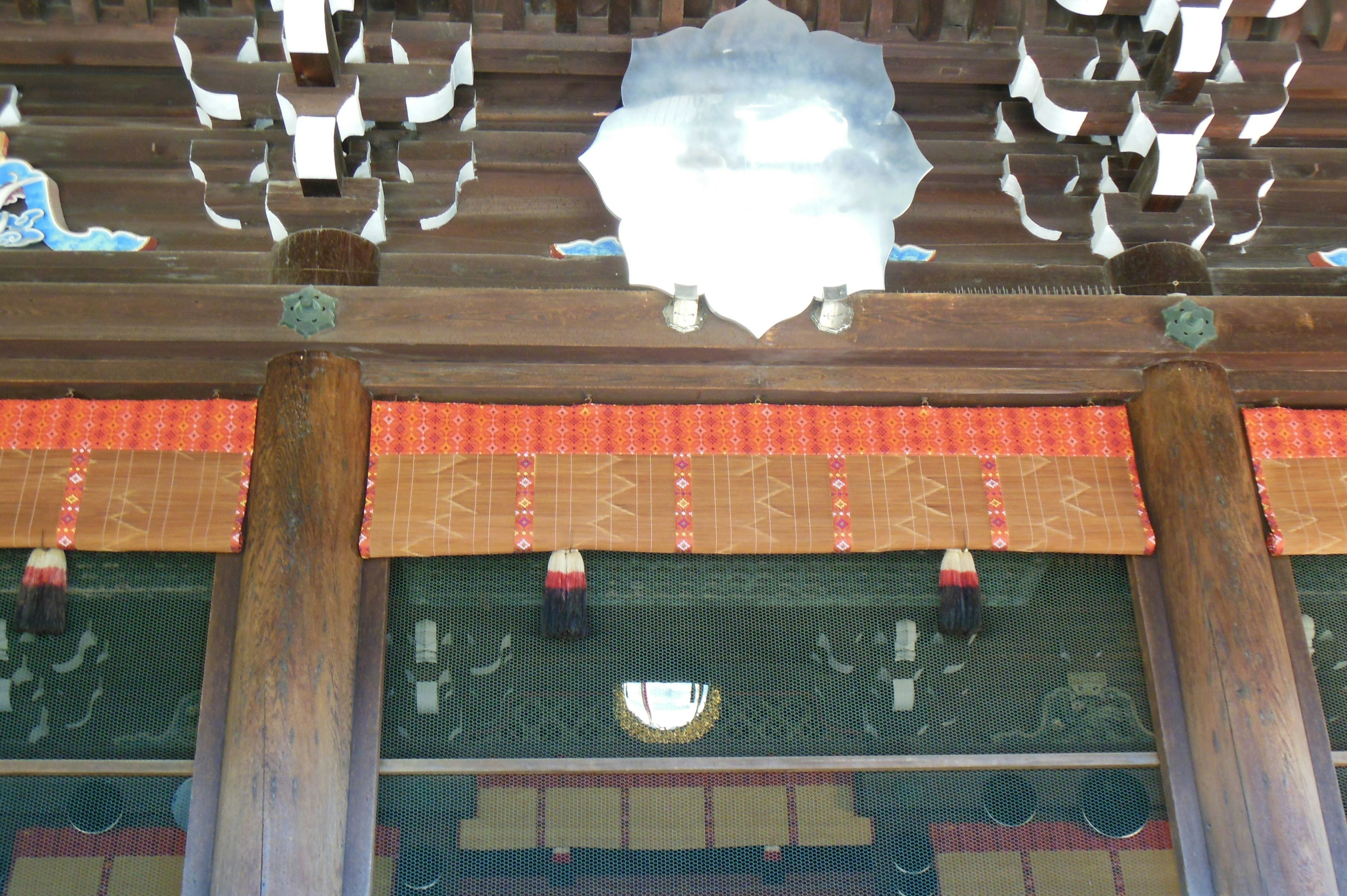 Interior decoration of traditional Japanese architecture featuring wooden pillars and red accents with geometric ceiling patterns