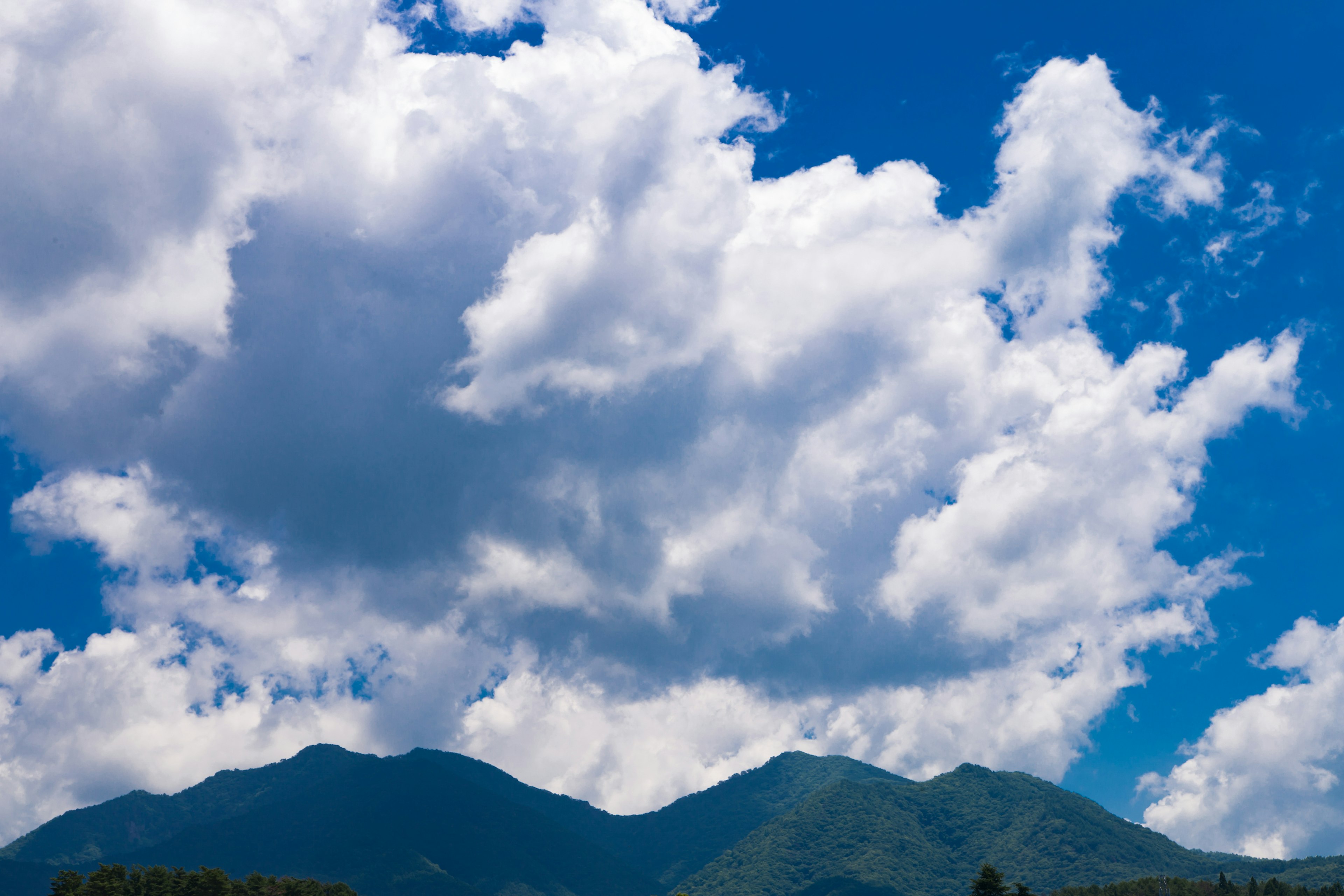 Paysage montagneux avec ciel bleu et nuages blancs duveteux