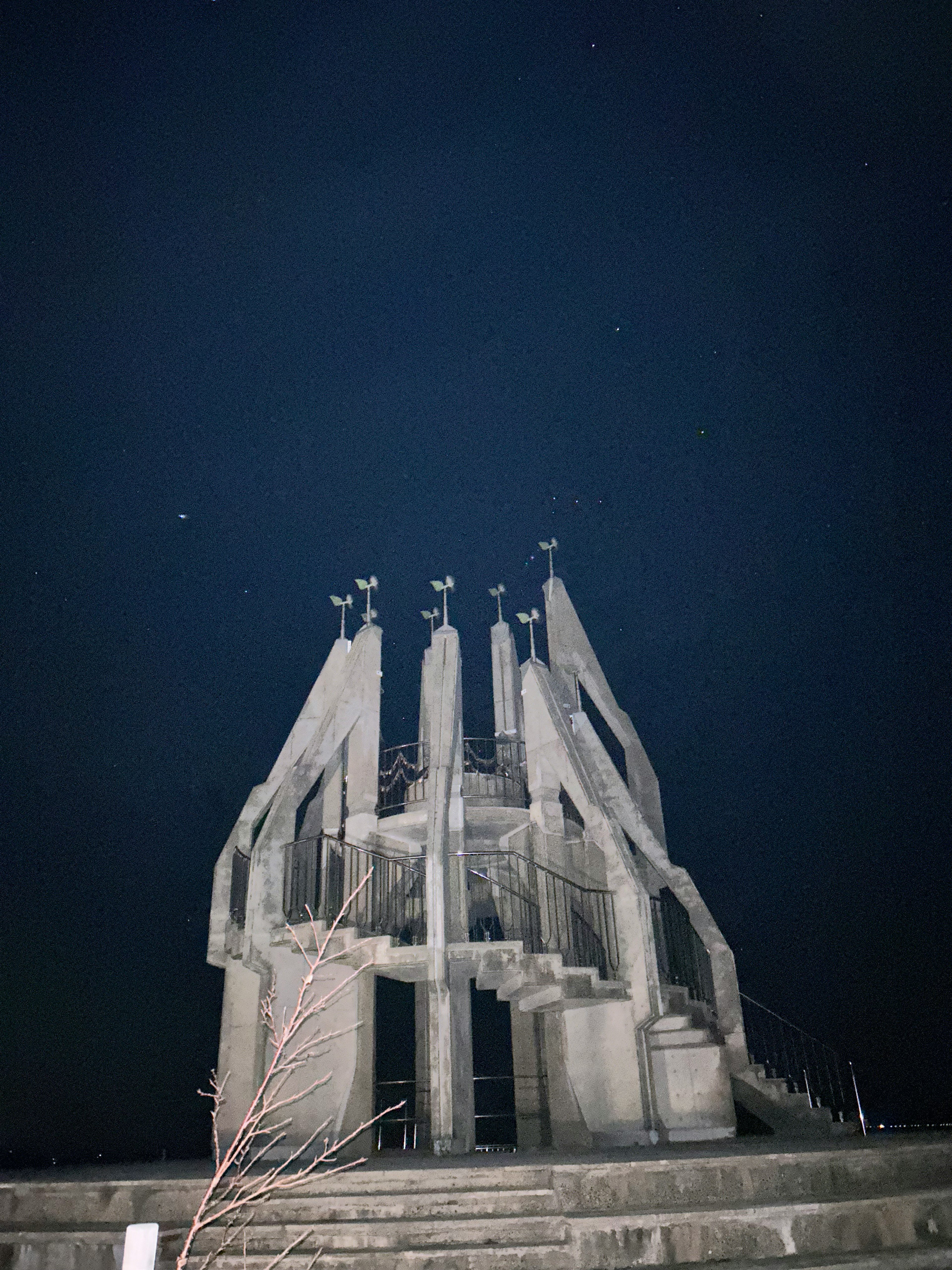 夜空の下に立つ近代的なコンクリート彫刻とその周囲の景観