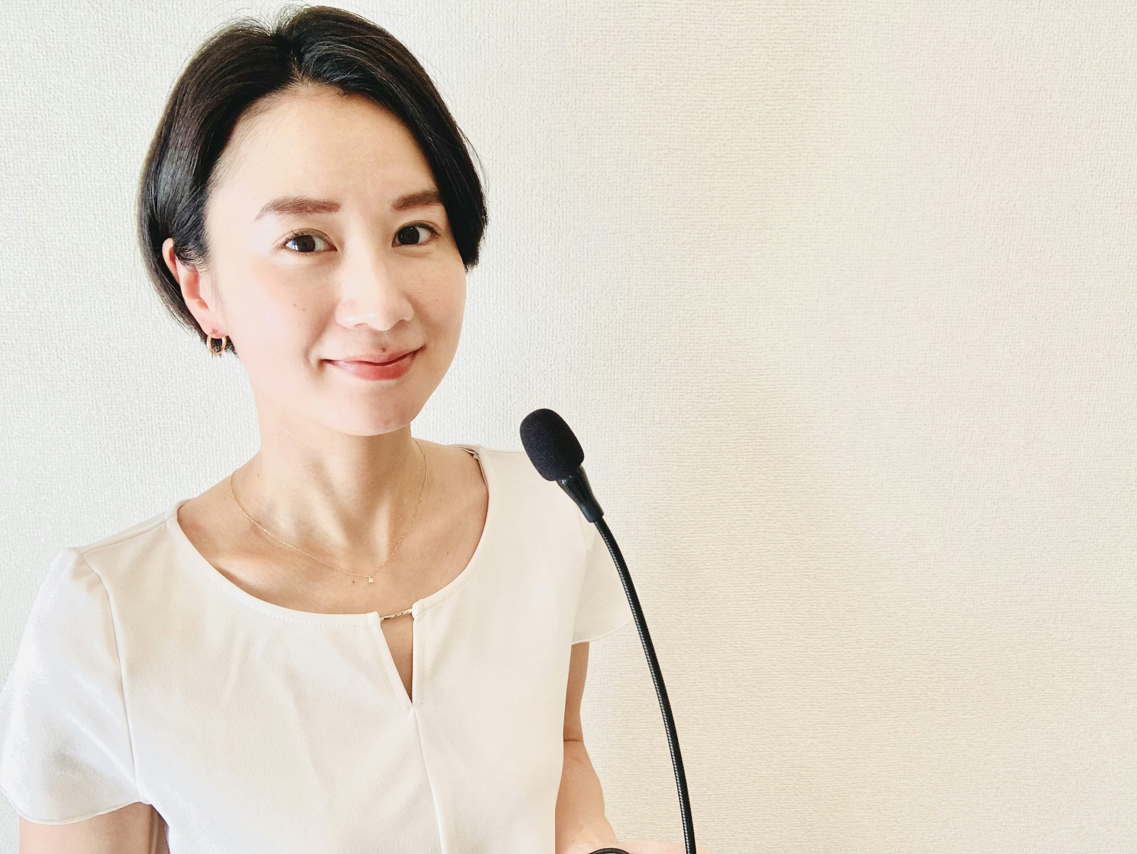 Une femme en blouse blanche souriant devant un microphone