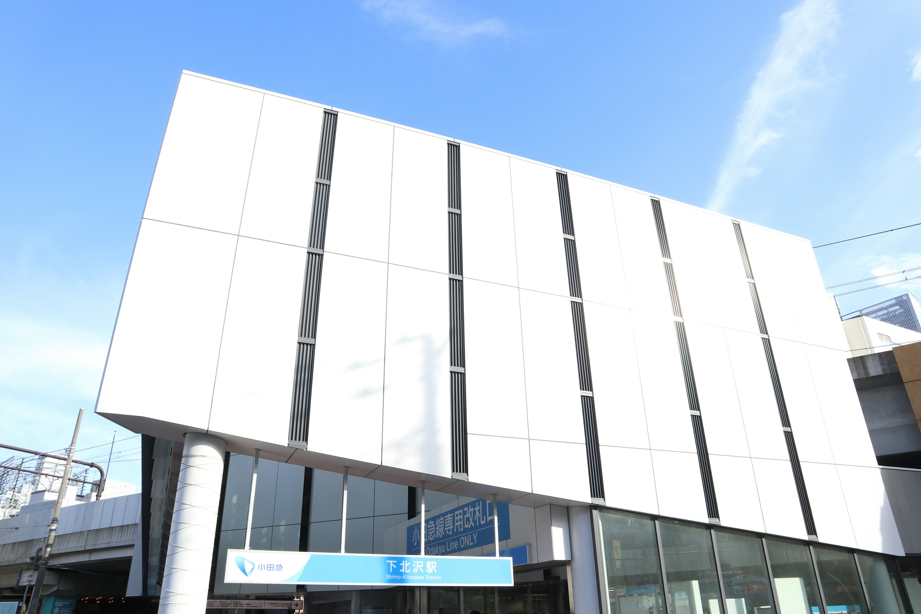 Modern white building with vertical black lines under blue sky