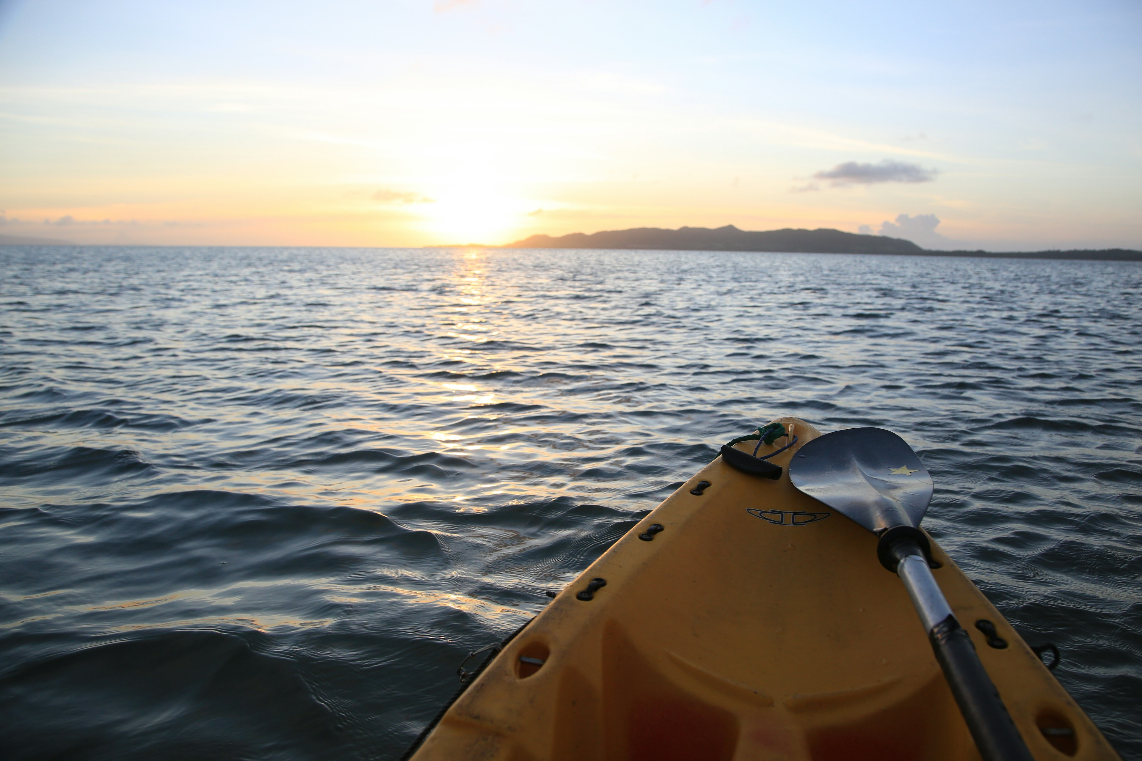 Pemandangan dari depan kayak dengan matahari terbenam di atas lautan