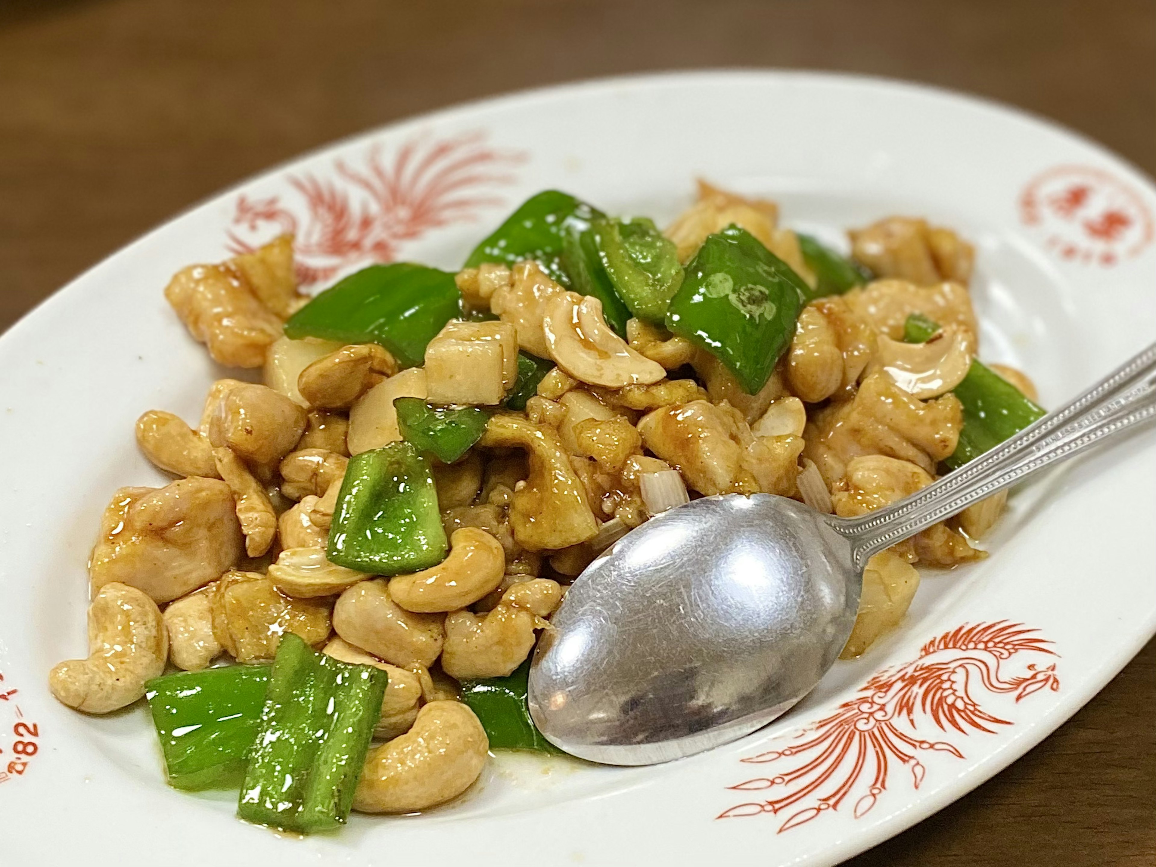 Gebratenes Hähnchen mit Cashewnüssen und grünen Paprika auf einem Teller serviert