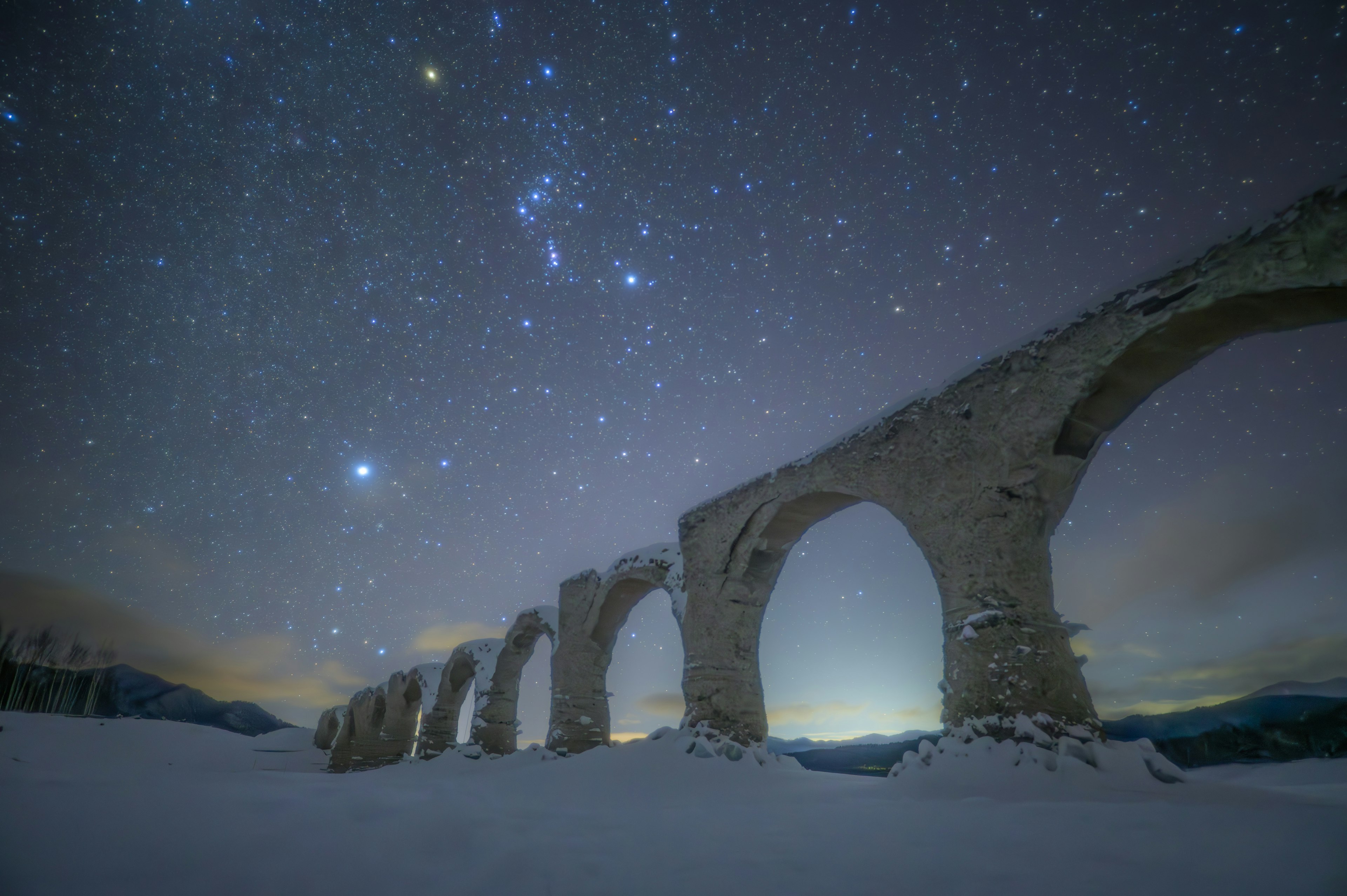 Acquedotto antico coperto di neve sotto un cielo stellato