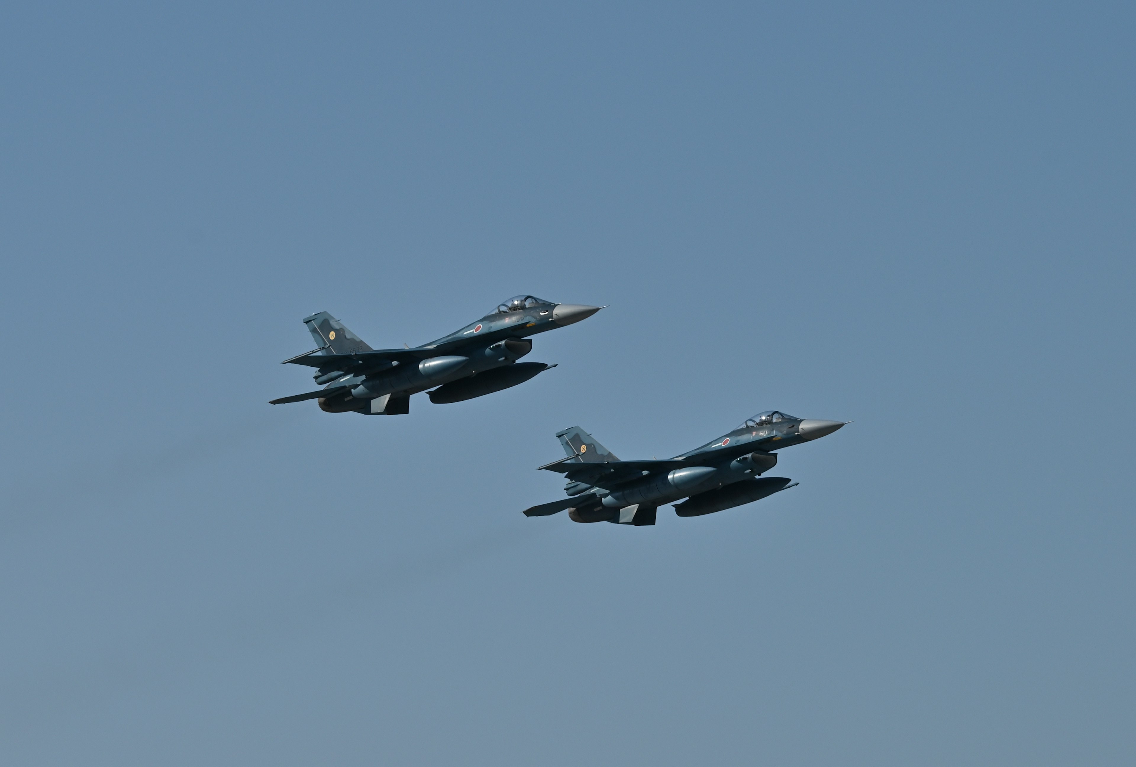 Two fighter jets flying in a clear blue sky