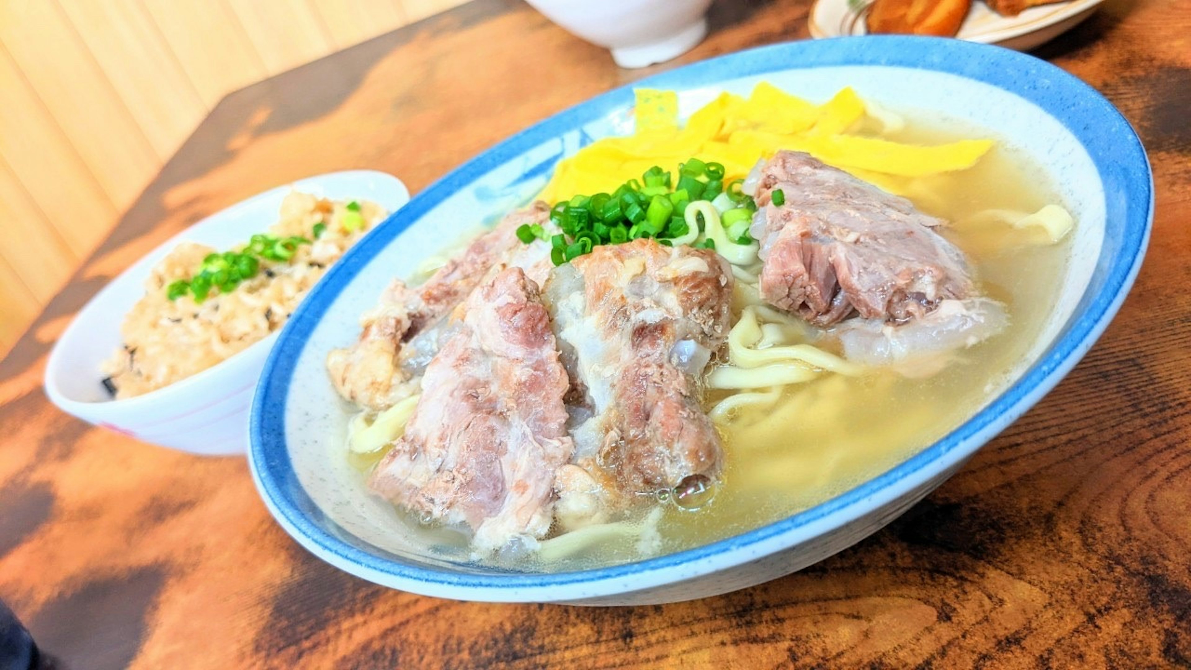 Un bol de soupe avec des nouilles surmonté d'oignons verts et de viande