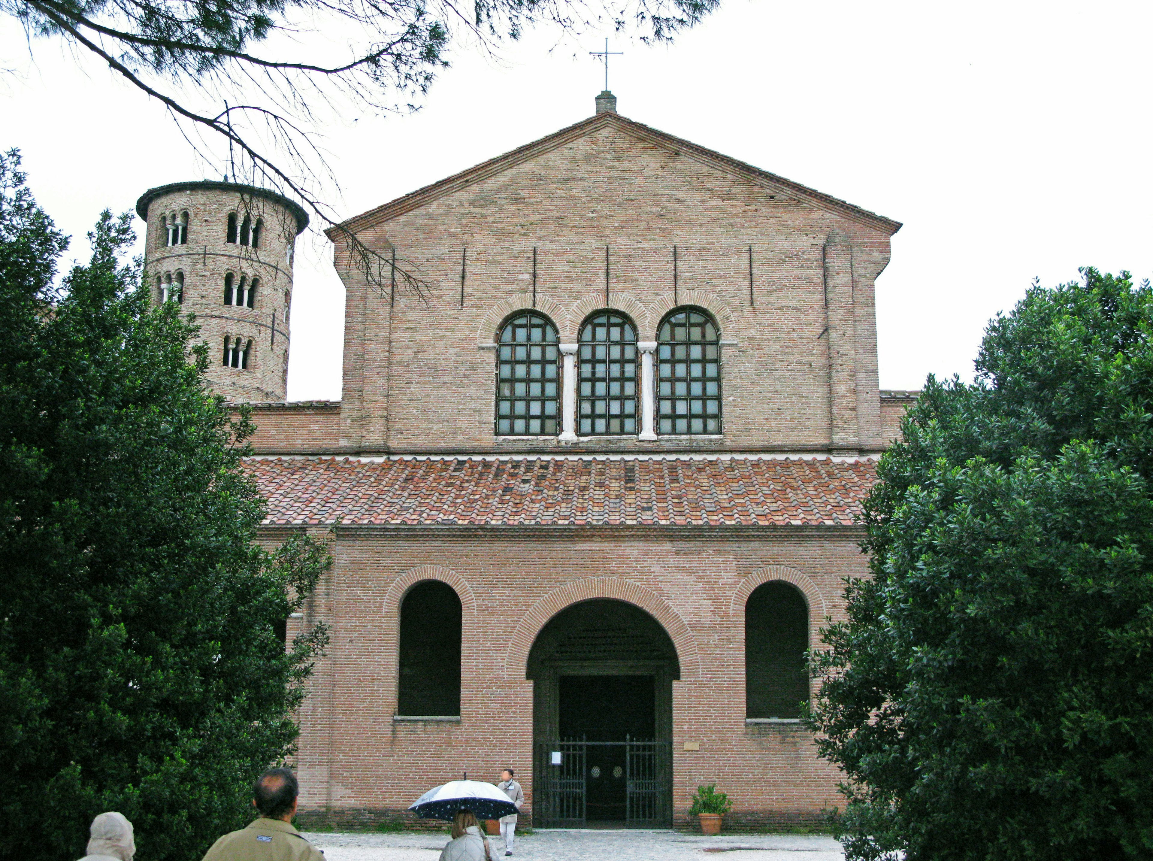 Esterno di una chiesa storica in mattoni circondata da vegetazione