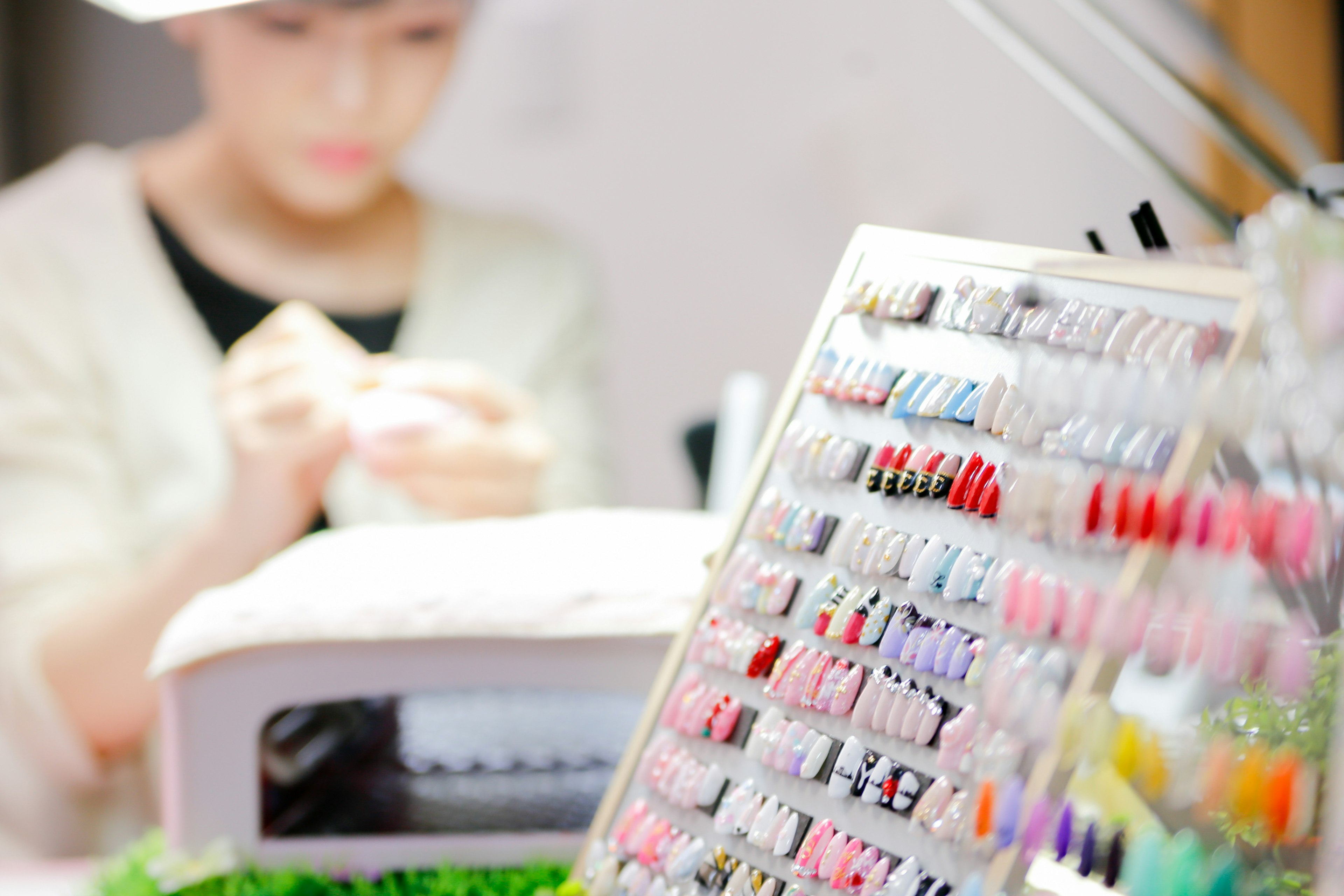 A woman working in a nail salon with a colorful nail polish display