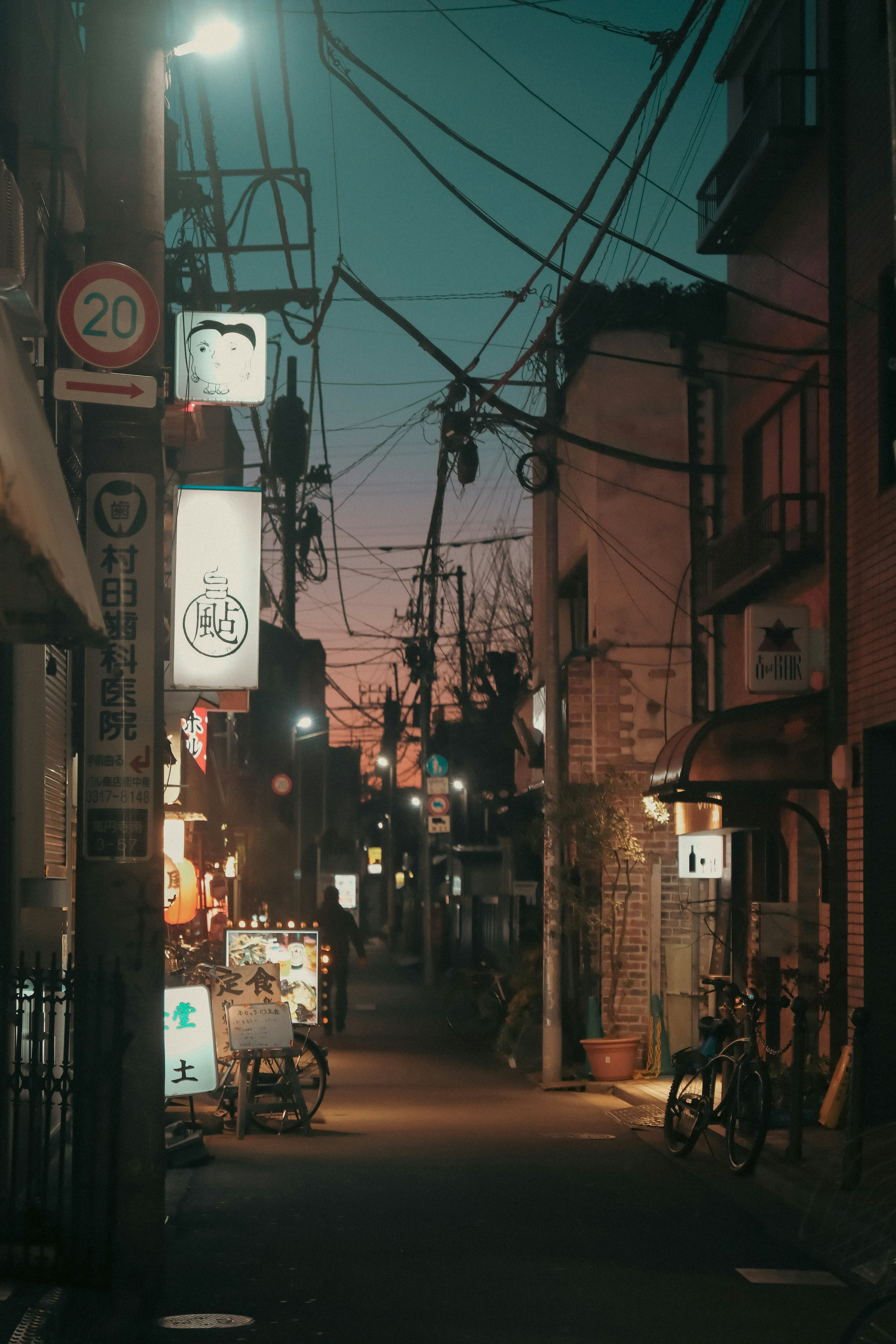 夜の街角の風景 電線が張り巡らされた狭い通り 商店の明かりが灯る