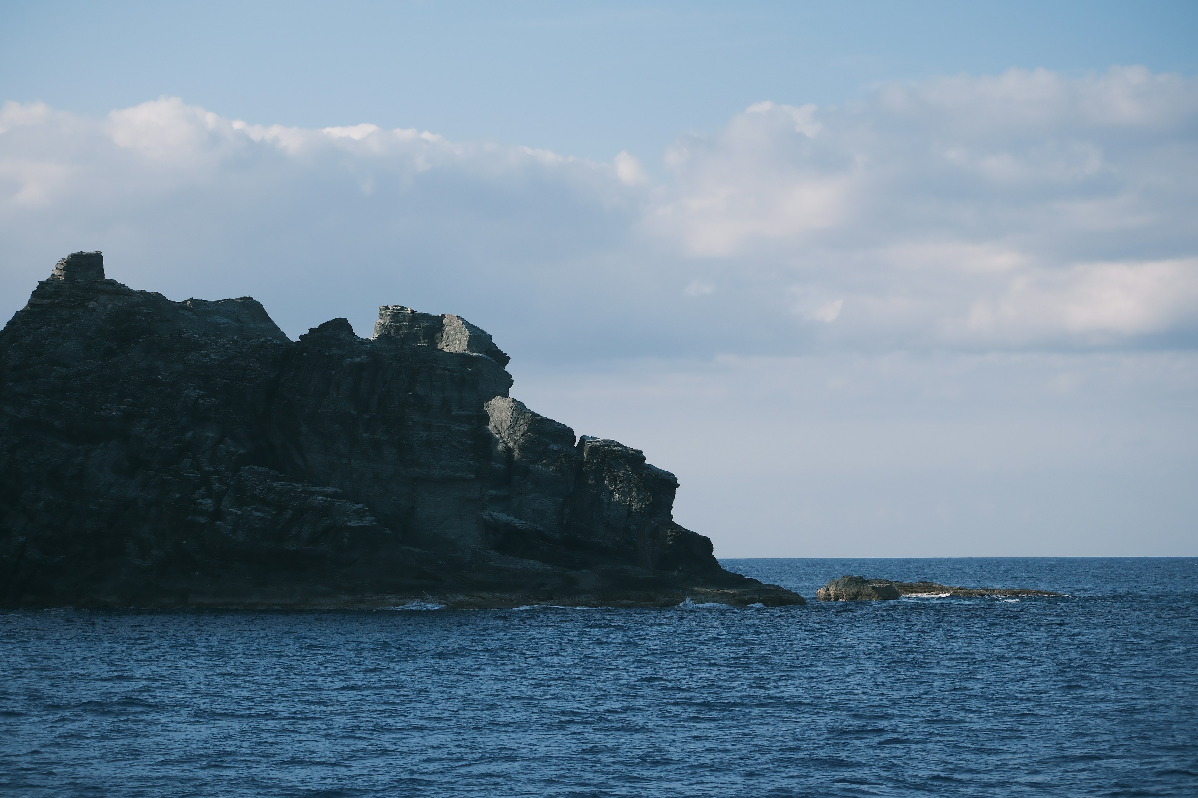 Costa rocciosa con onde oceaniche e cielo nuvoloso