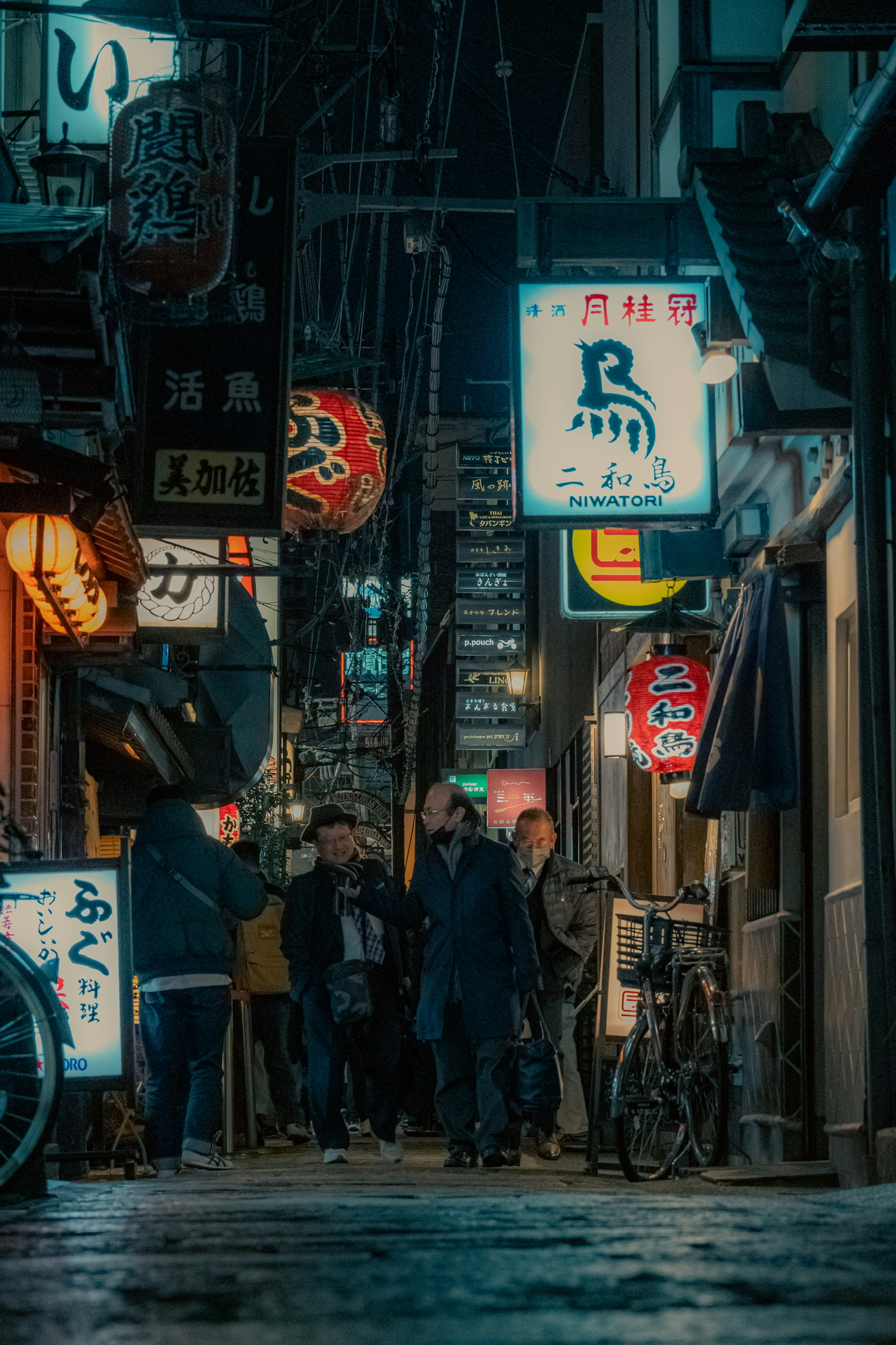 Bustling alley at night with people and neon signs