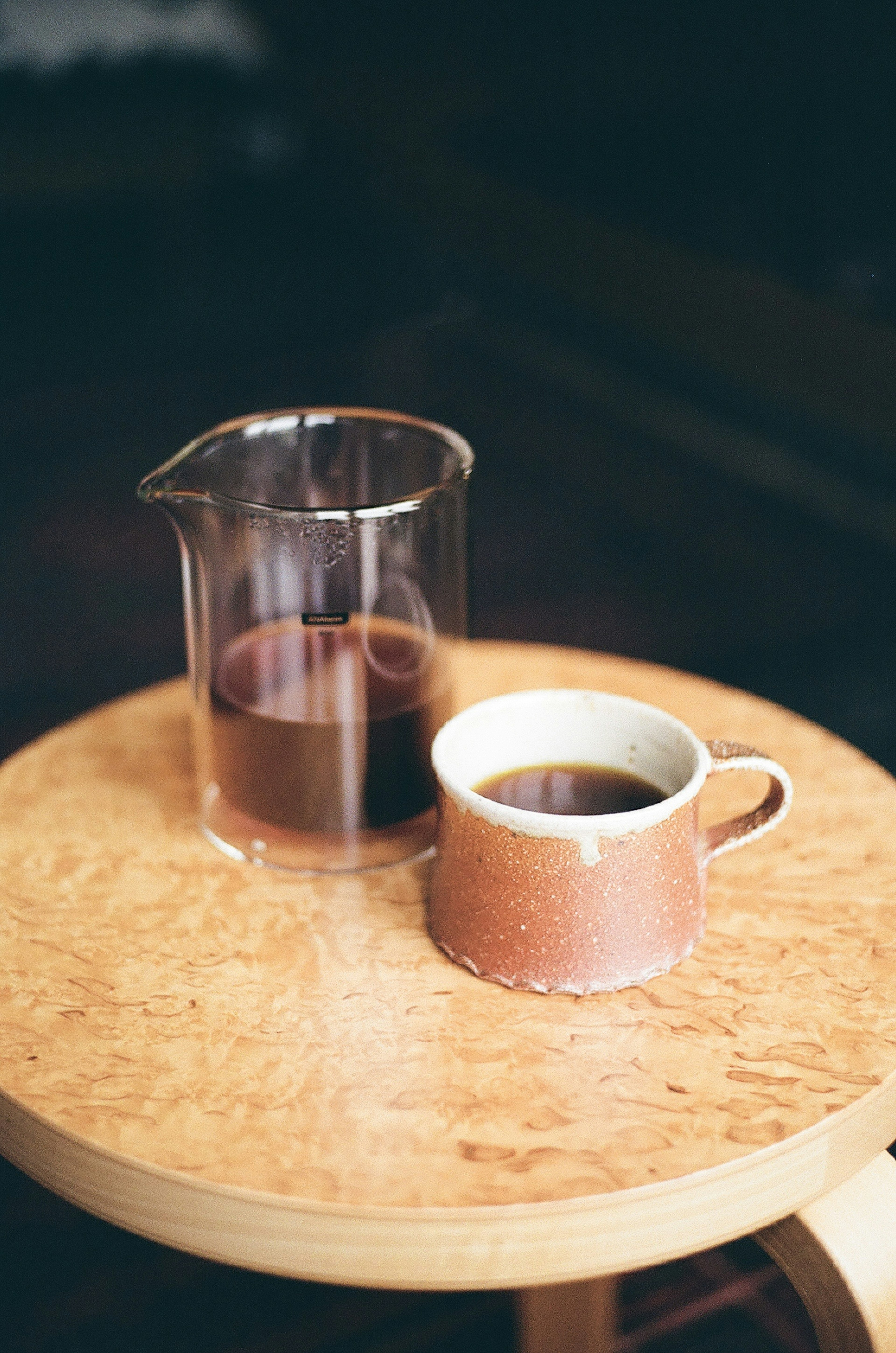 Una escena simple de una taza de café y una jarra sobre una mesa de madera