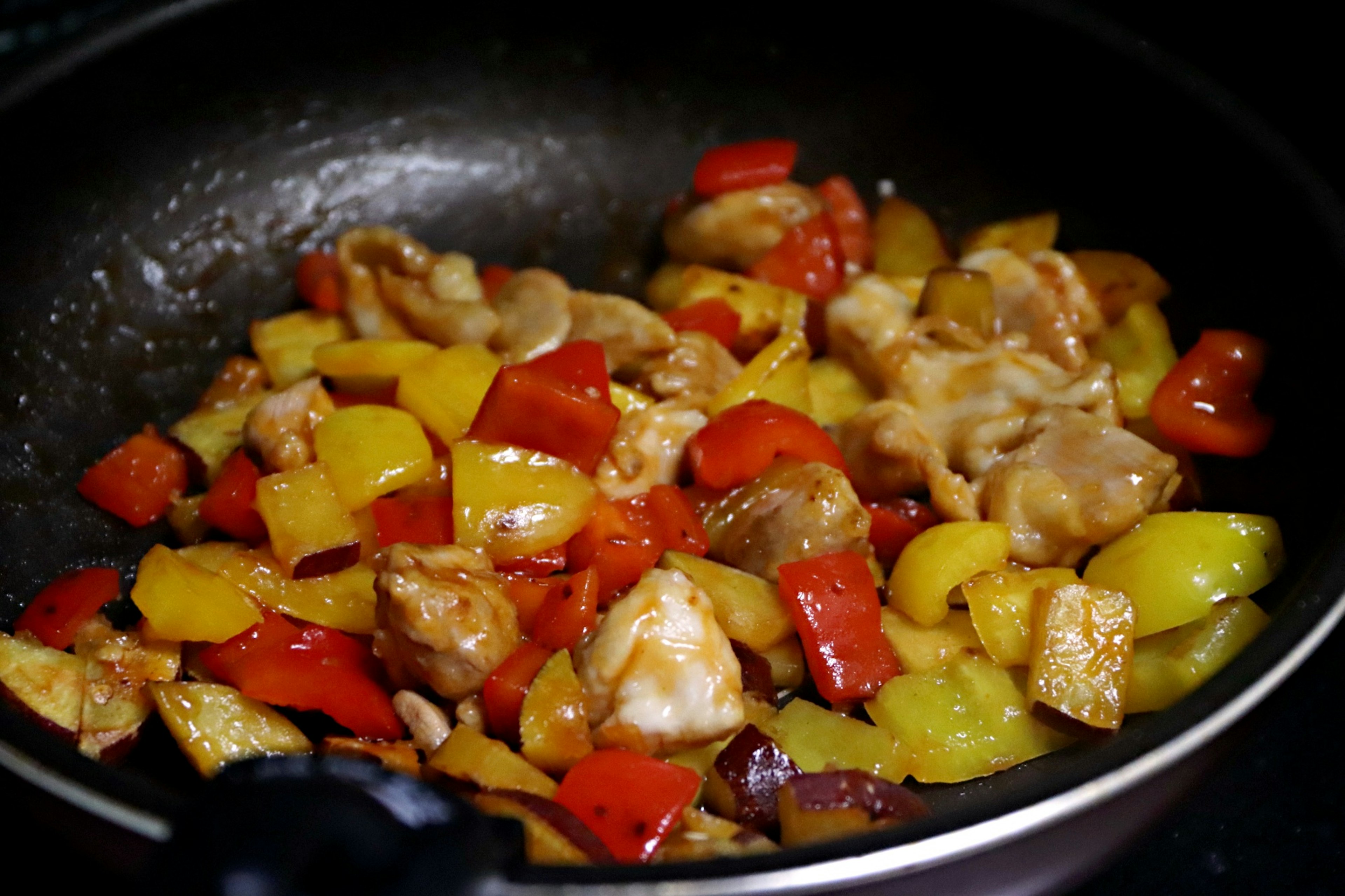 Stir-fried chicken with colorful bell peppers in a frying pan