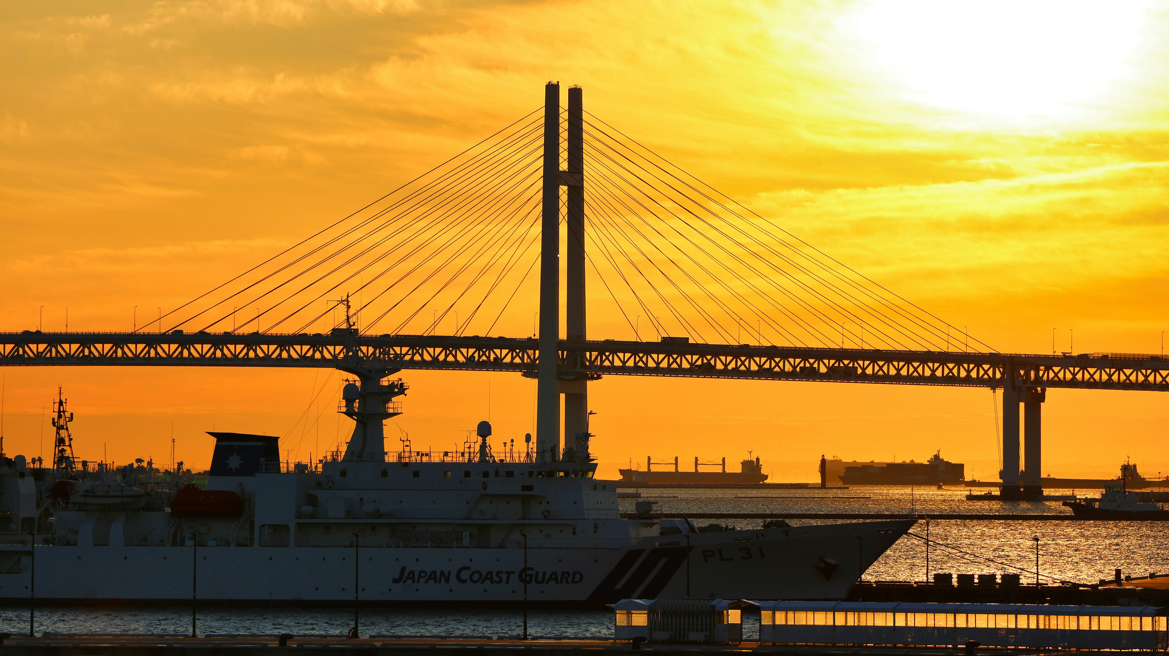 Silhouette del ponte della baia di Yokohama con una nave al tramonto