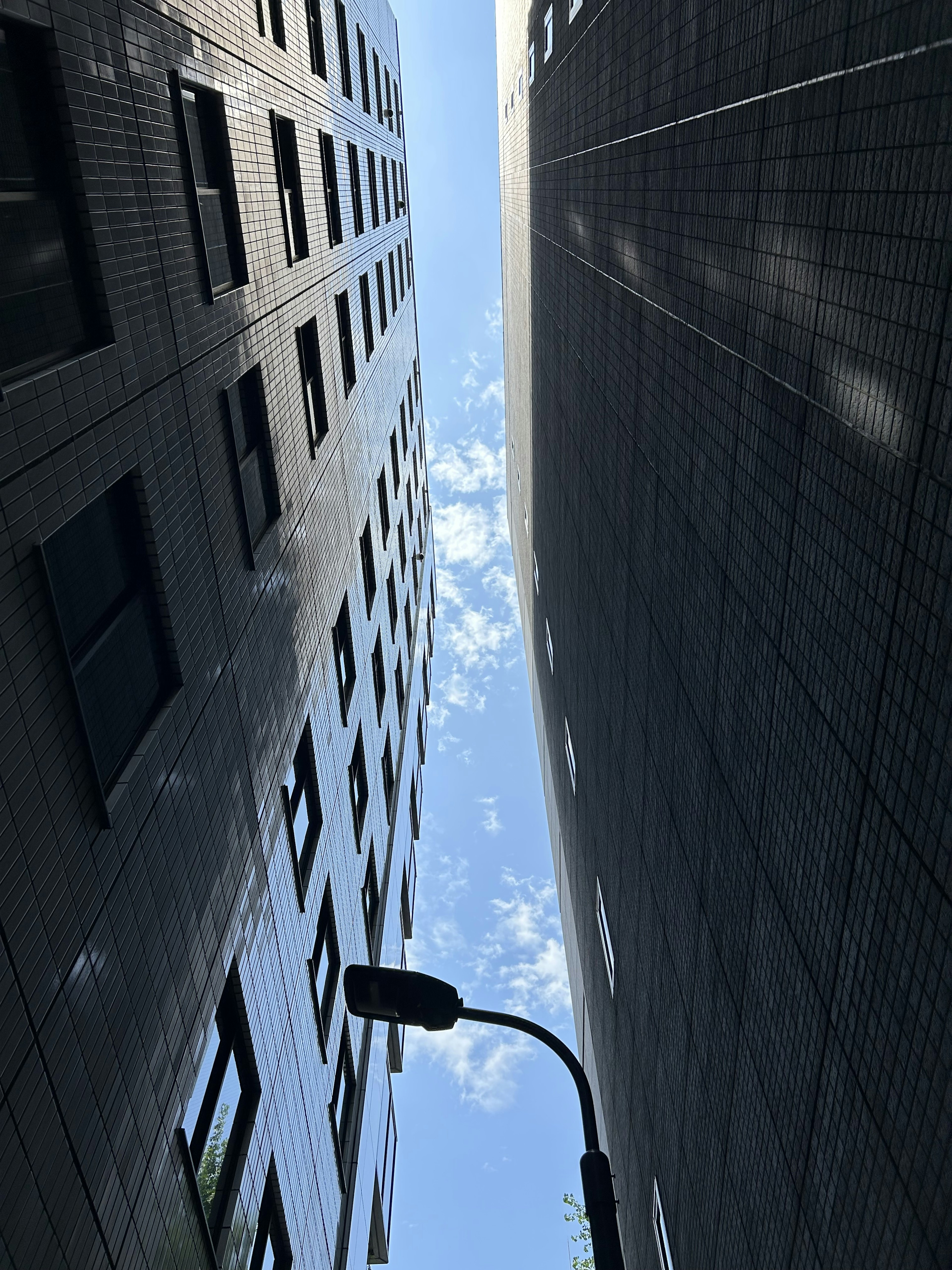 View of blue sky and clouds between tall buildings