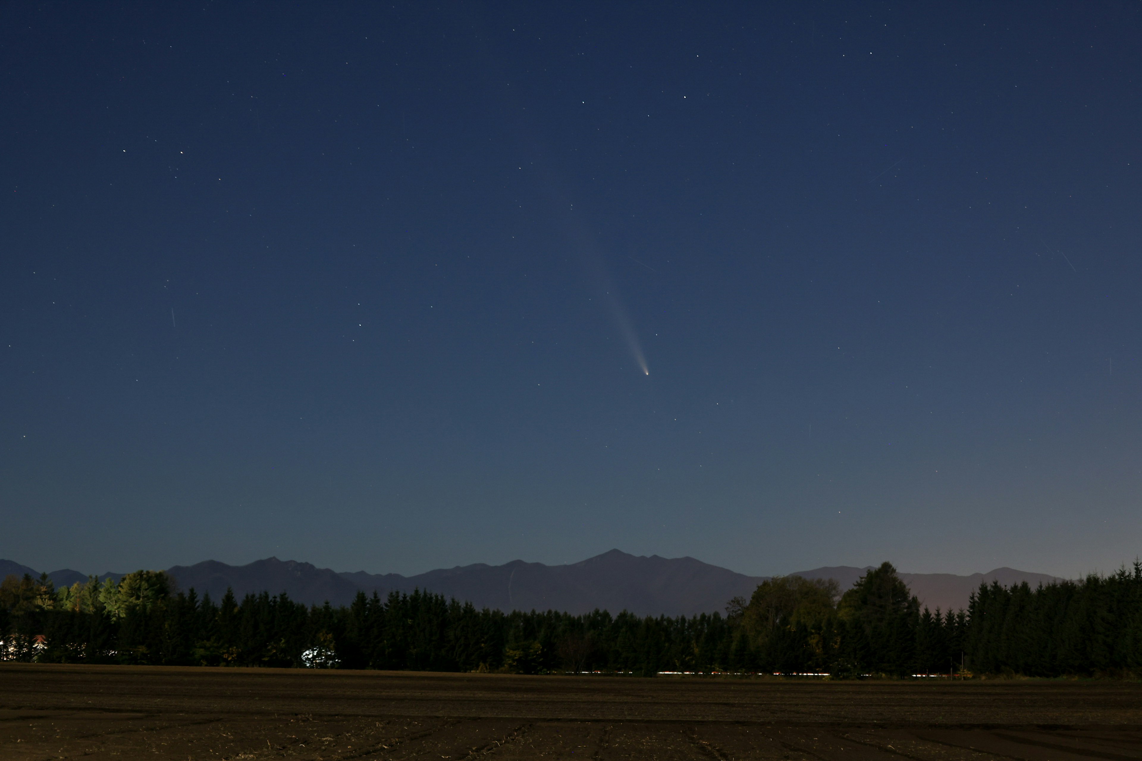 夜空に輝く彗星と山々の風景