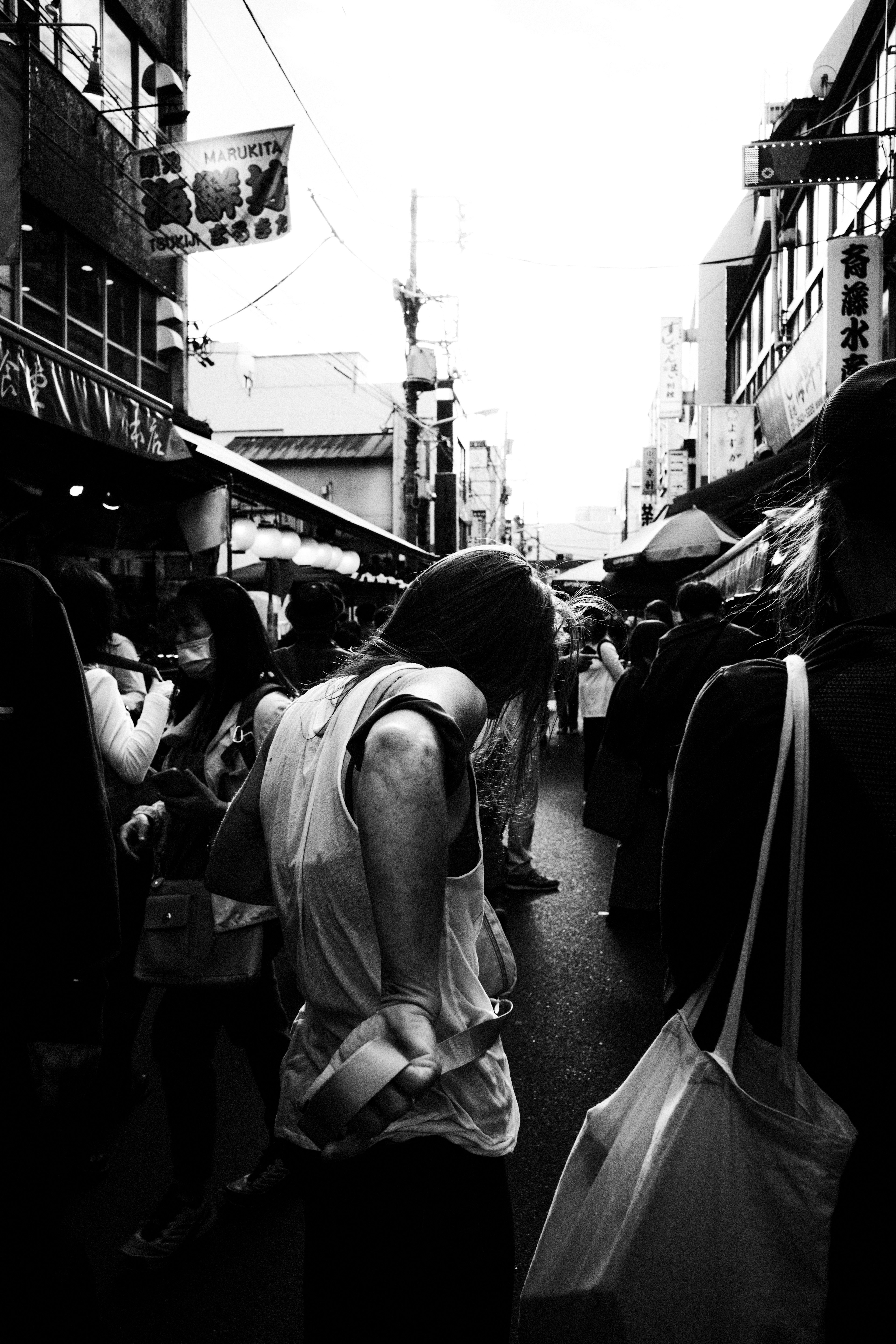 A person with their back turned in a bustling market street filled with people