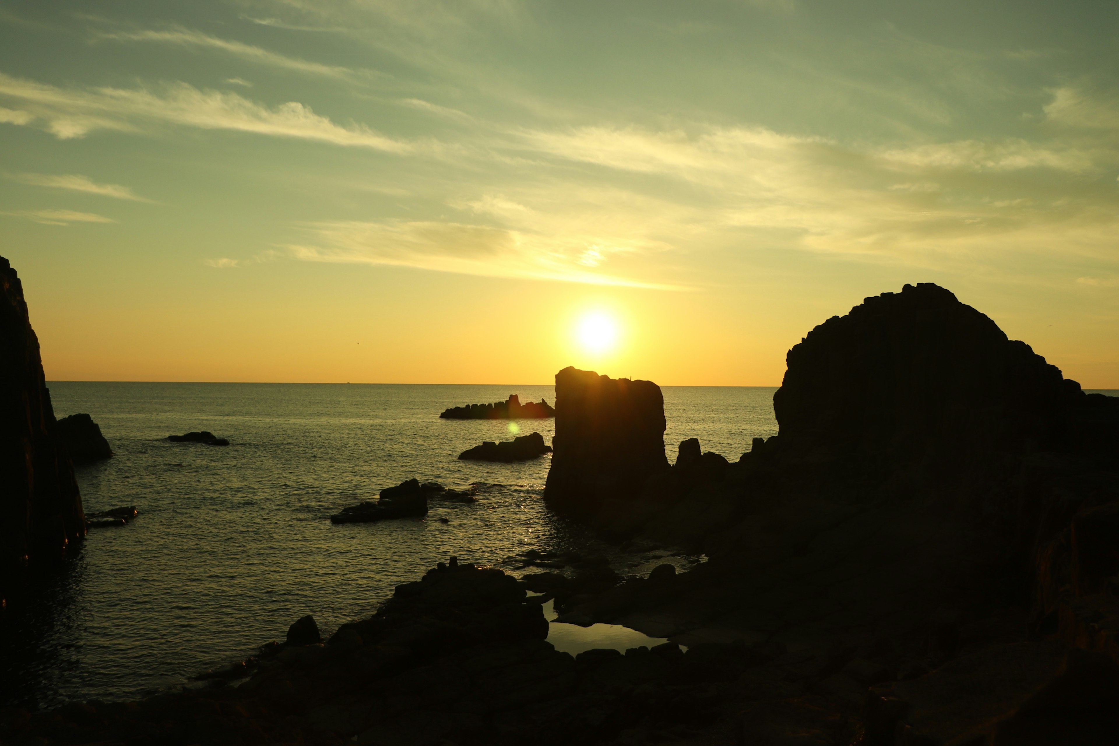 Rocas costeras en silueta contra un vibrante atardecer