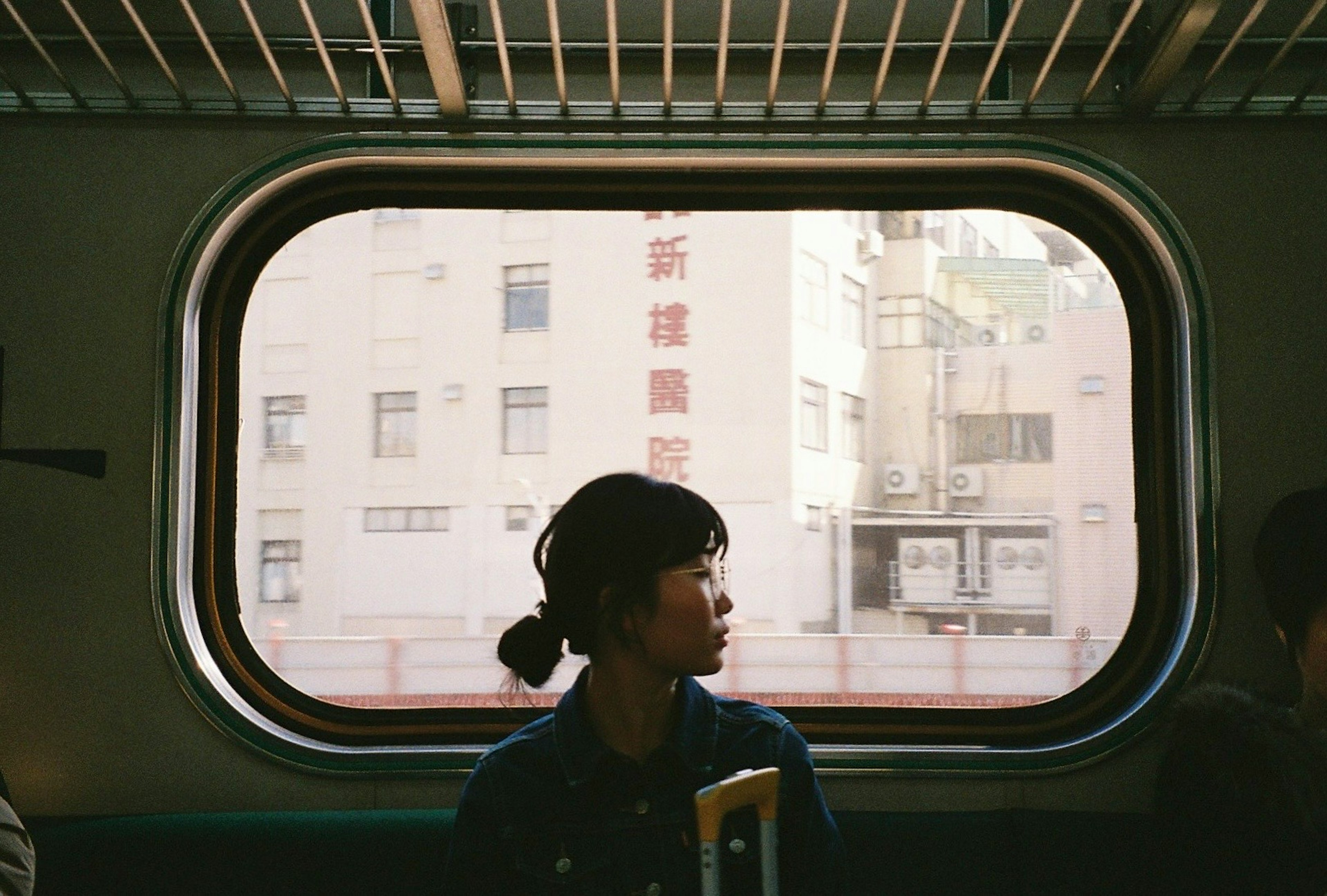 一名女性透過火車窗戶凝視城市風景的側面