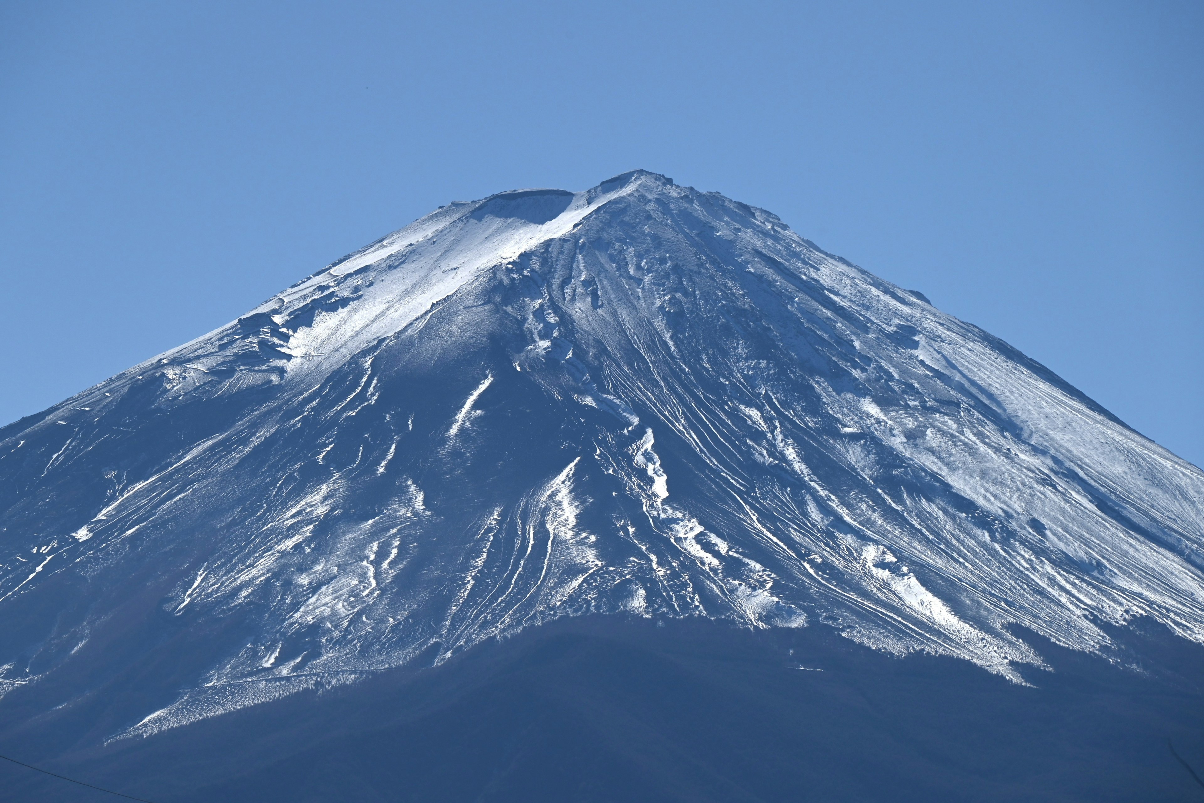 Close-up of Mount Fuji covered in snow against a blue sky