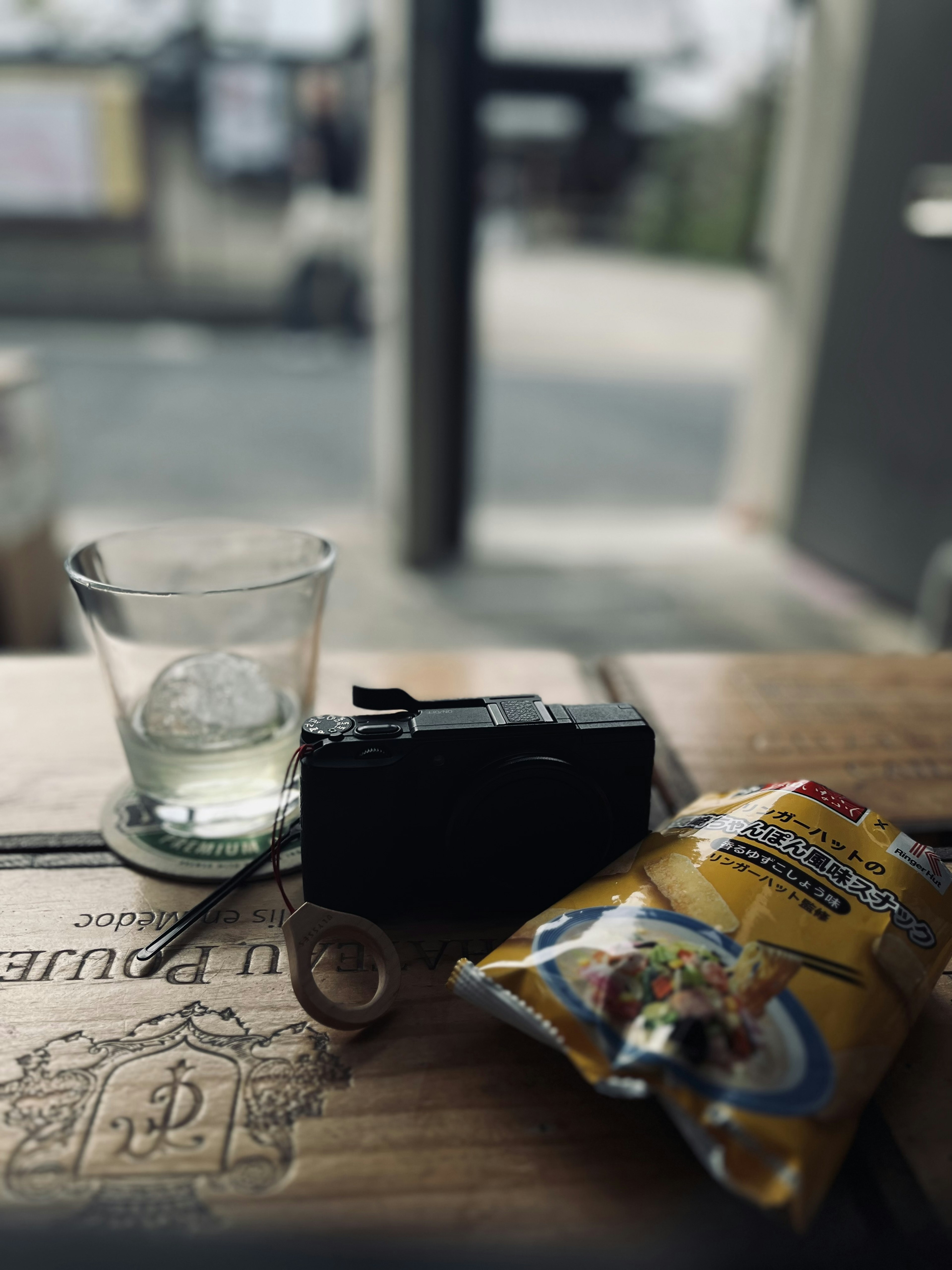 Una cámara, un bocadillo y un vaso sobre una mesa de madera