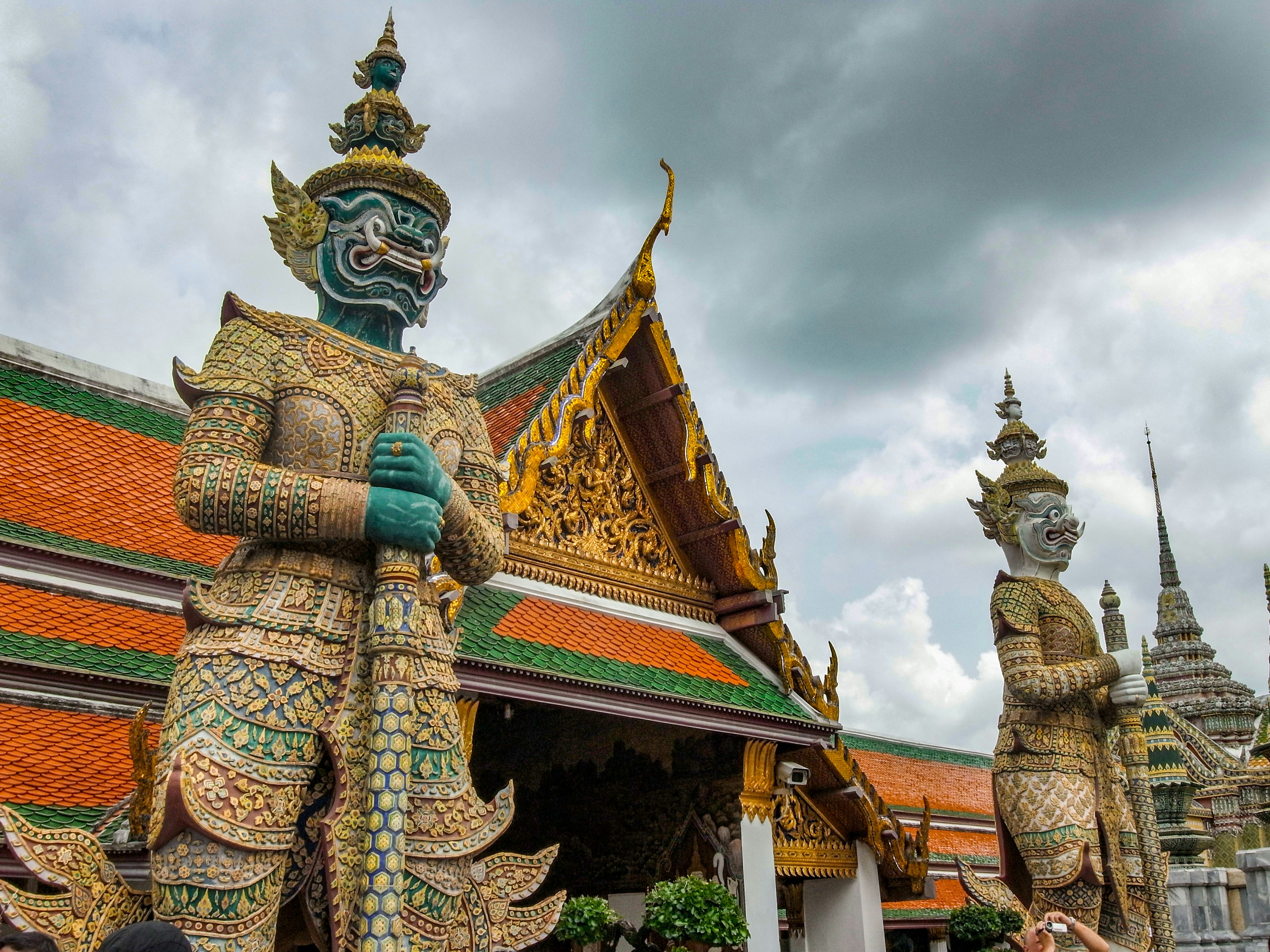 Due enormi statue di guardiani si ergono davanti a un tempio thailandese