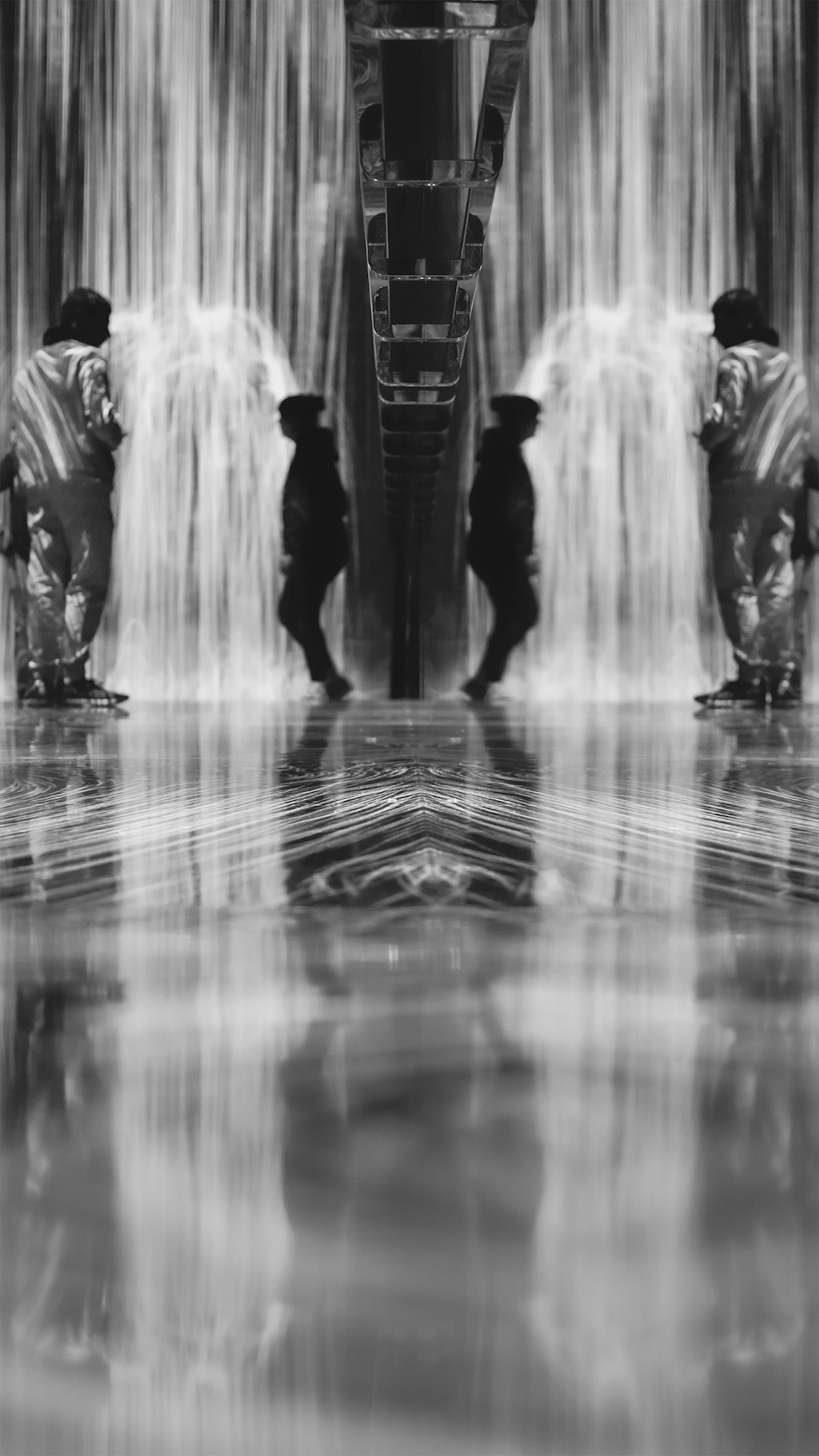 Two children playing in front of a black and white water curtain