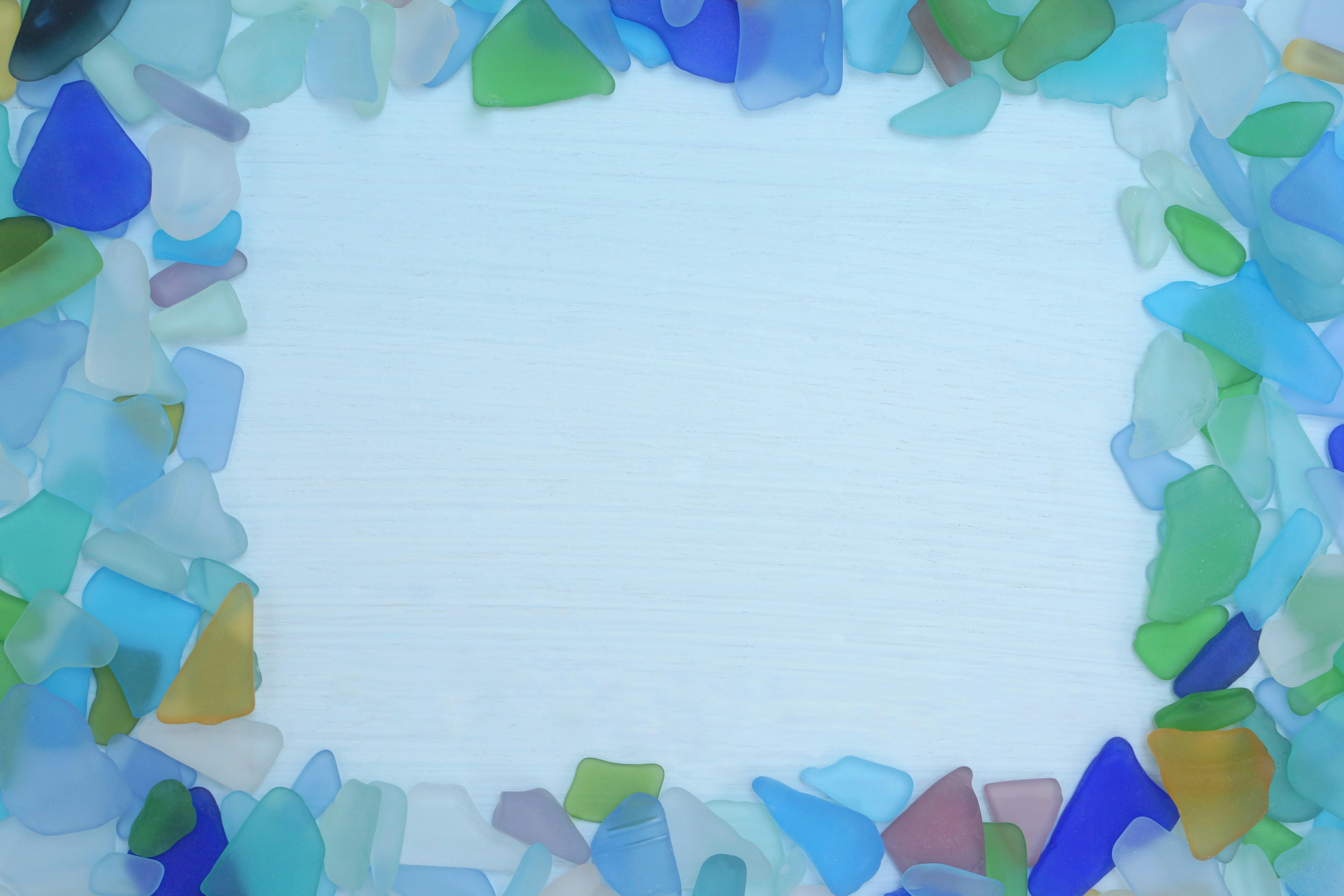 Colorful sea glass pieces framing a white background