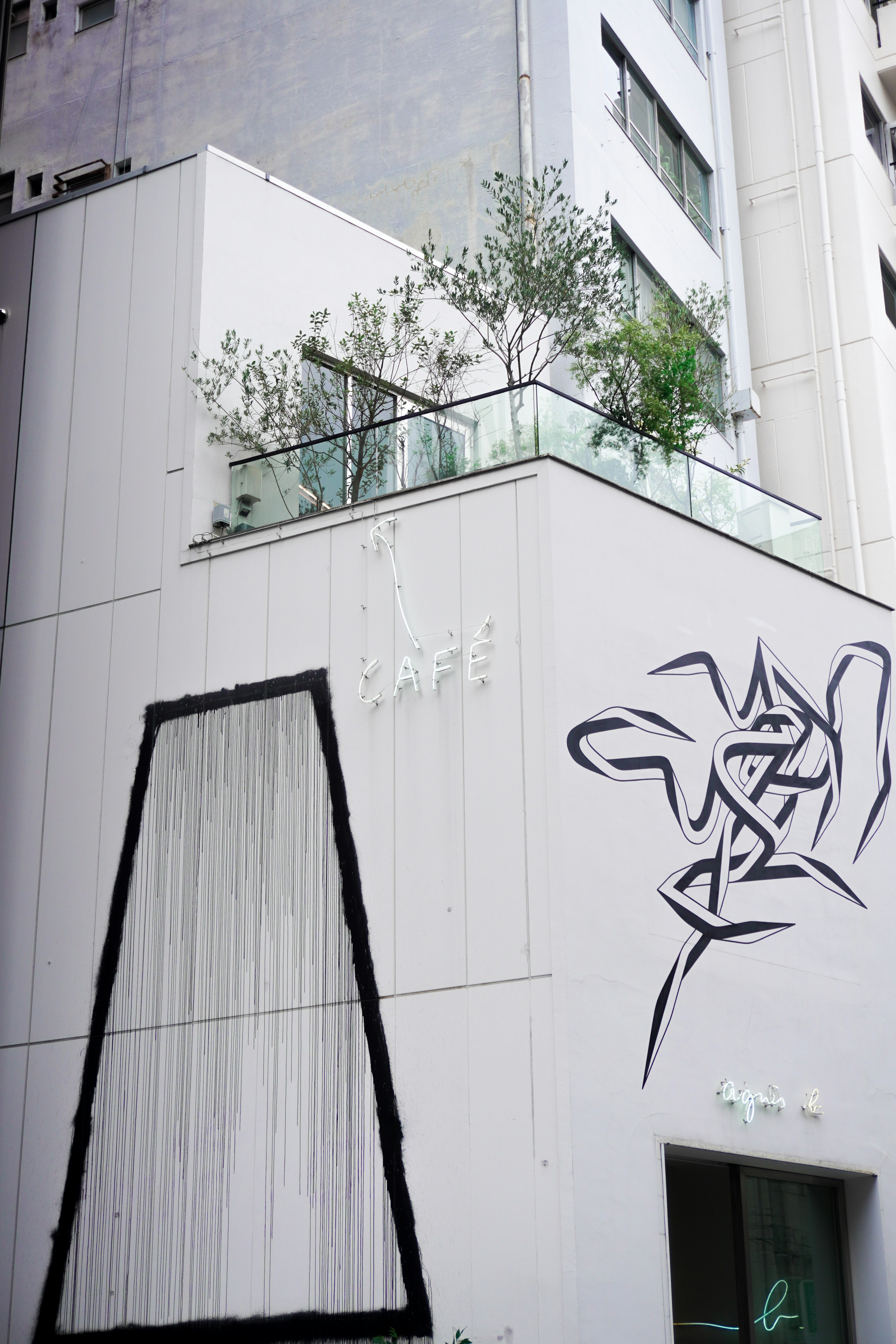 Abstract graffiti on a white building exterior with greenery on the rooftop