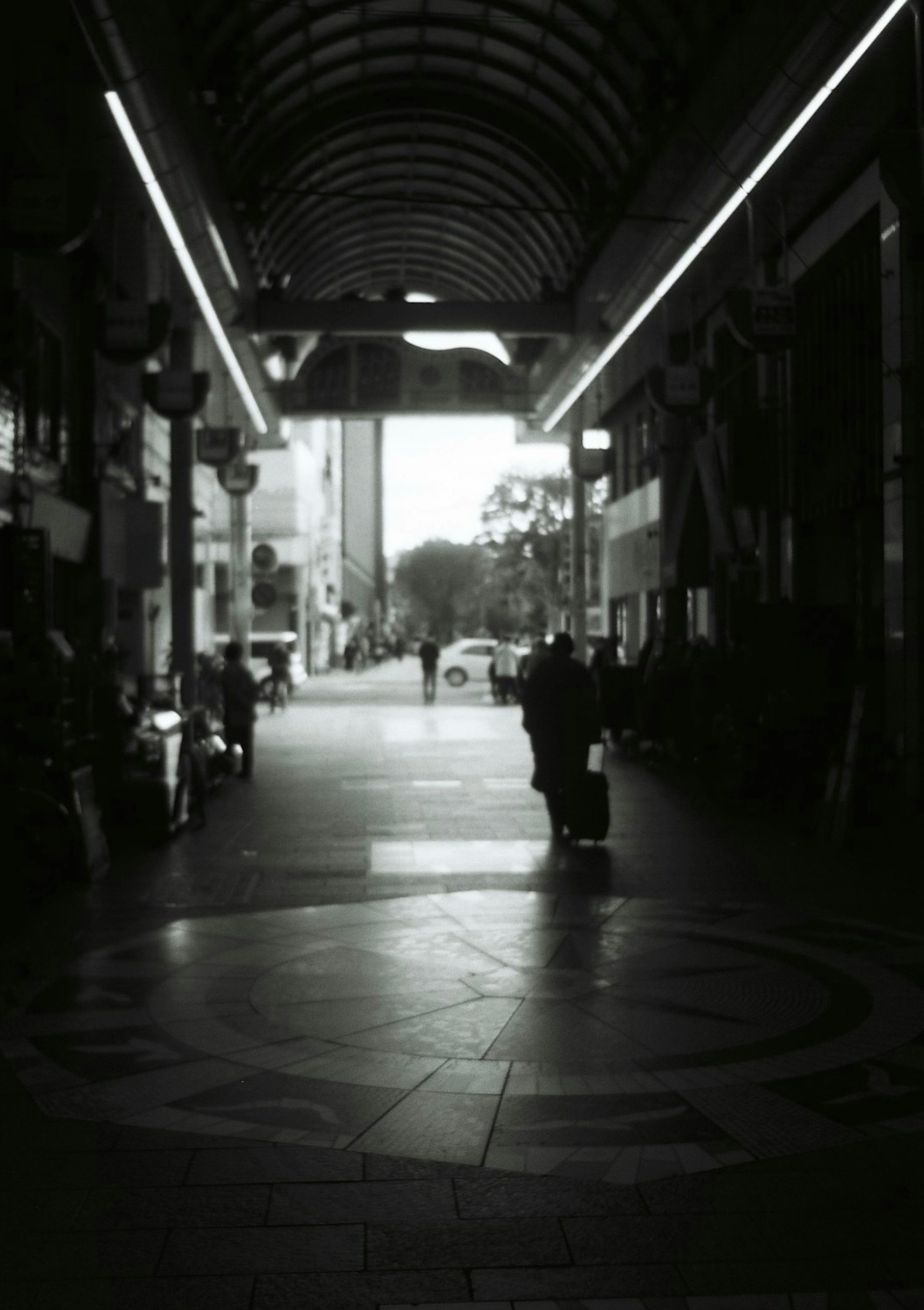 Un corredor comercial en blanco y negro armoniosamente bello con personas que pasan y luz que entra