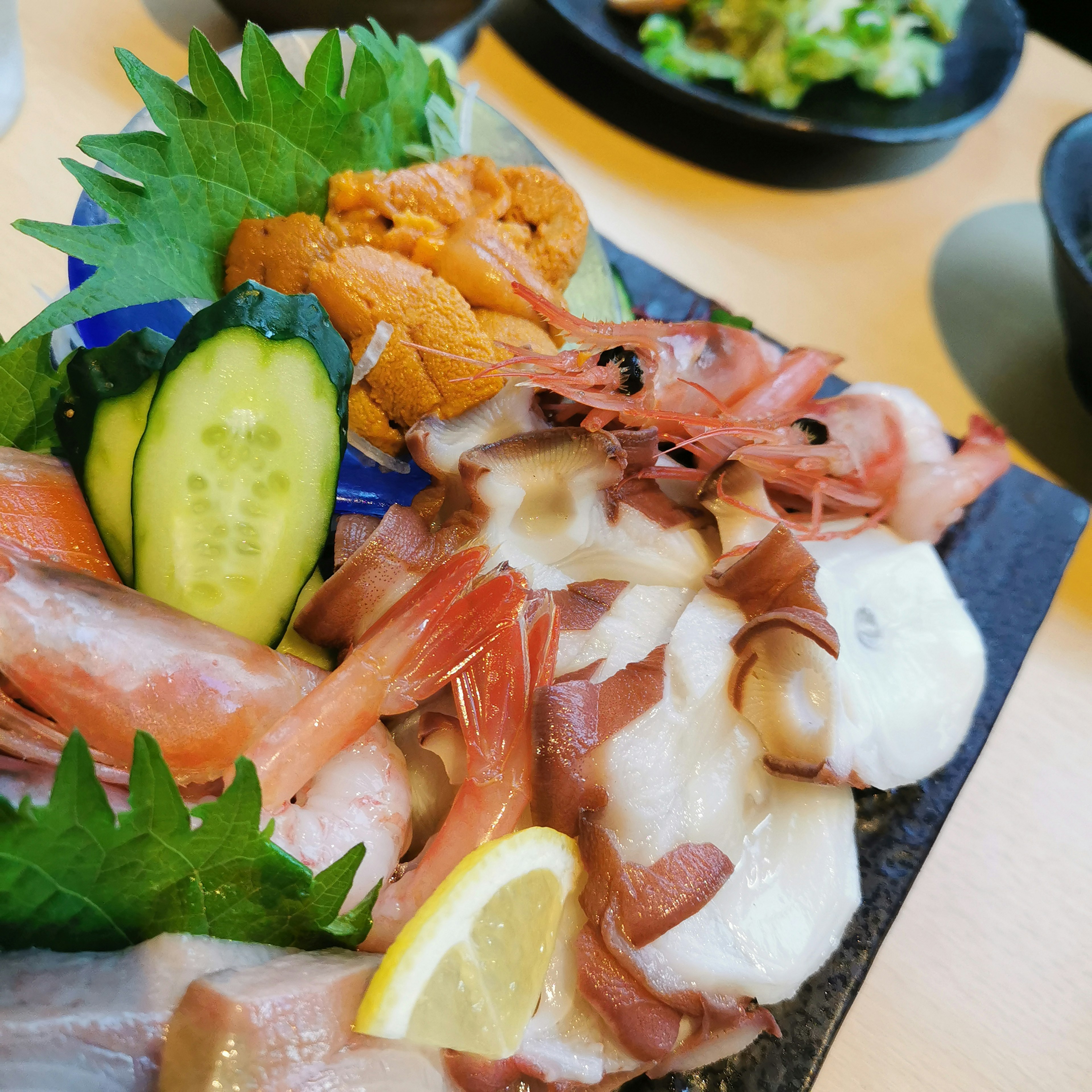 Plato de sashimi y mariscos frescos con varios mariscos coloridos y verduras dispuestas de manera hermosa