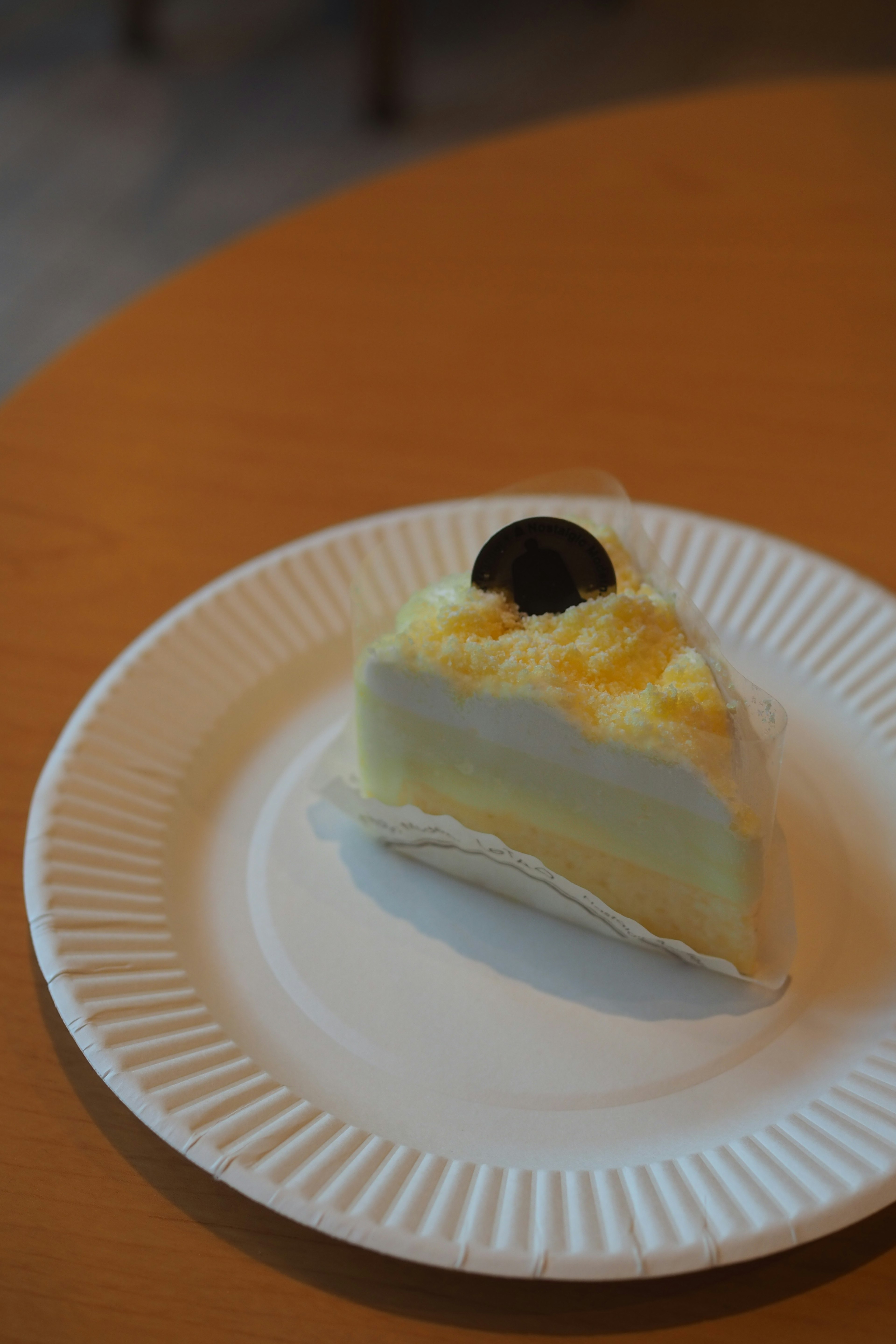 Una rebanada de pastel de crema blanca con una pieza de chocolate negro encima