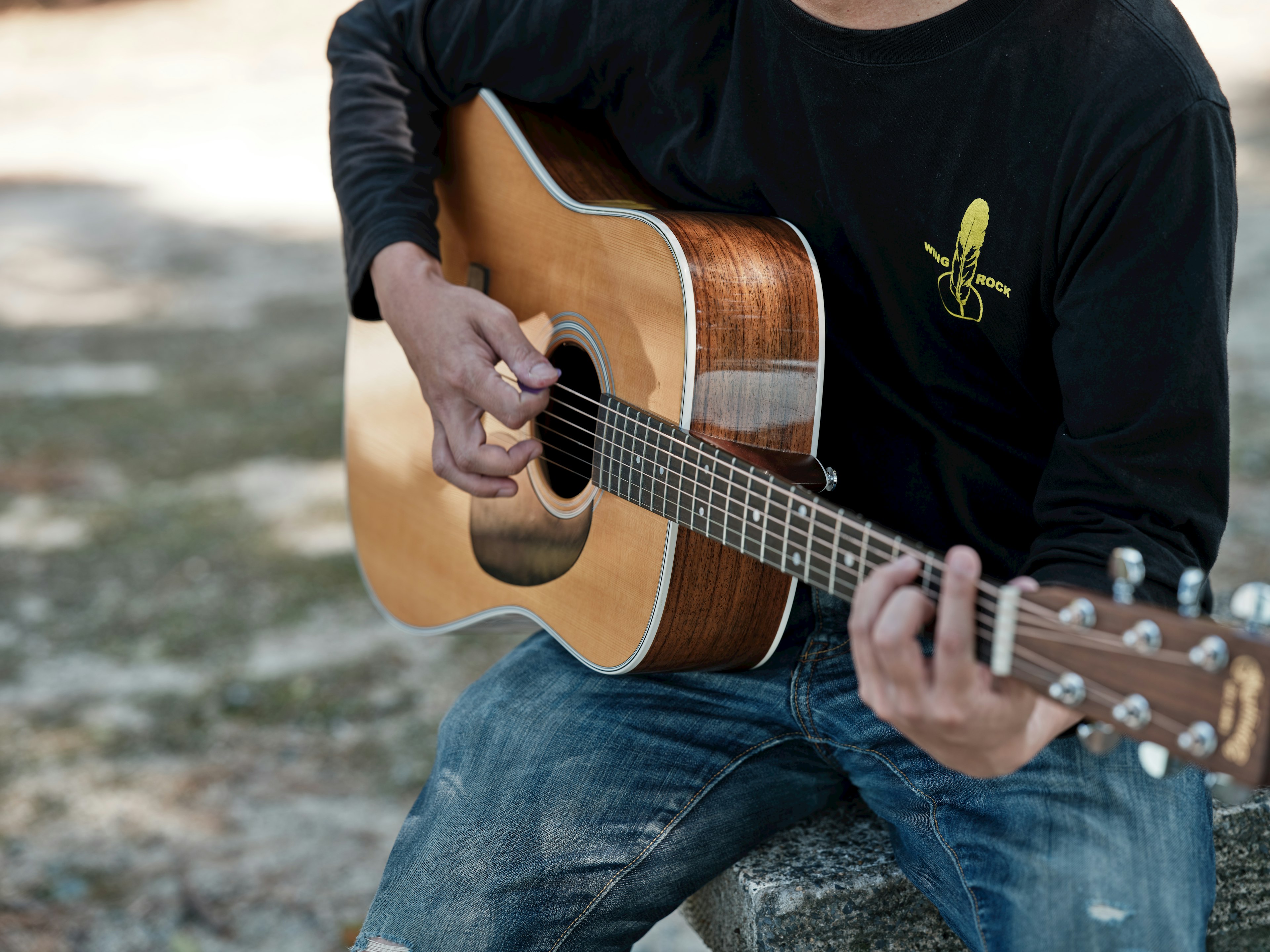 Nahaufnahme eines Mannes, der draußen eine Akustikgitarre spielt