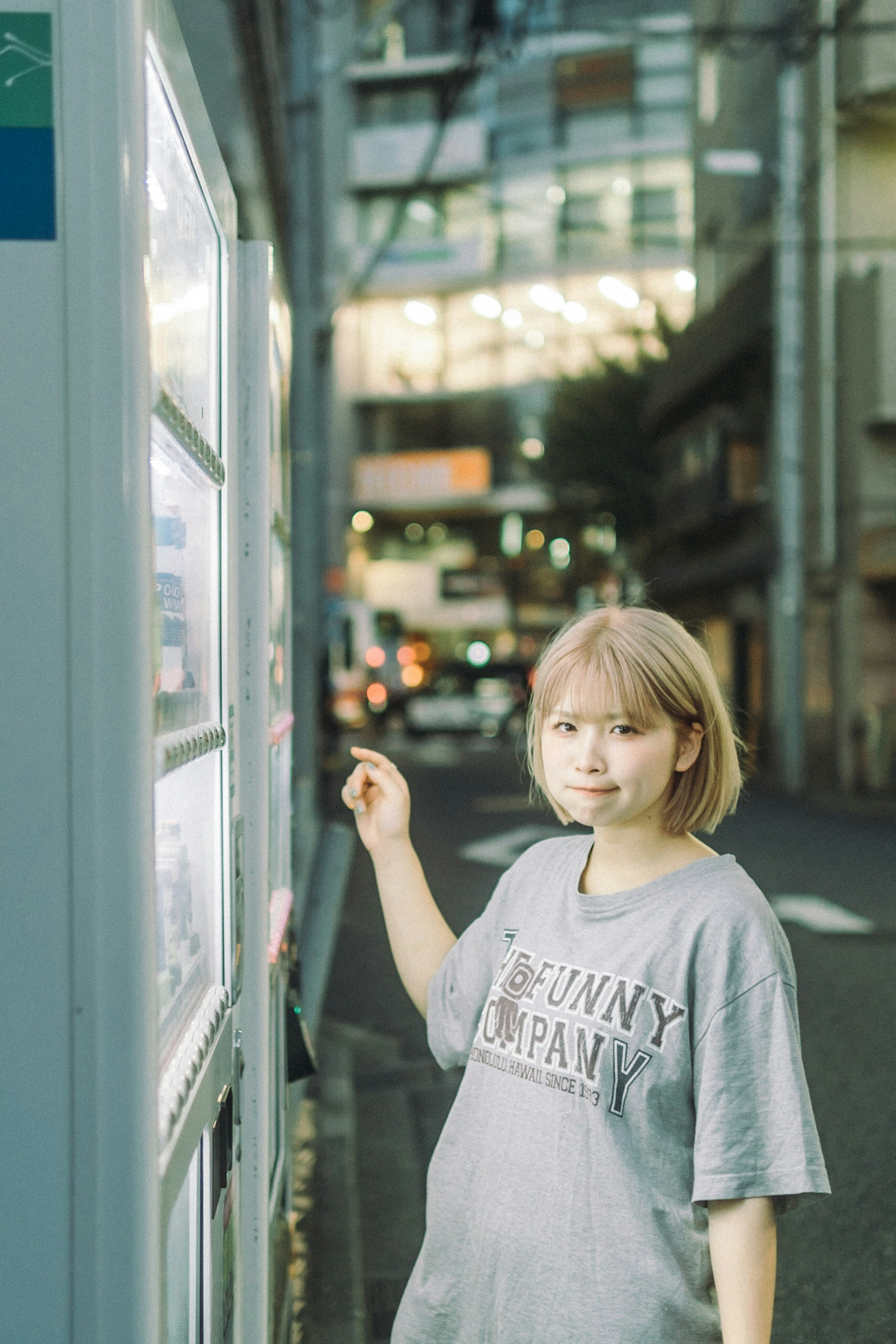 街中の自動販売機でメニューを見ている短髪の女性