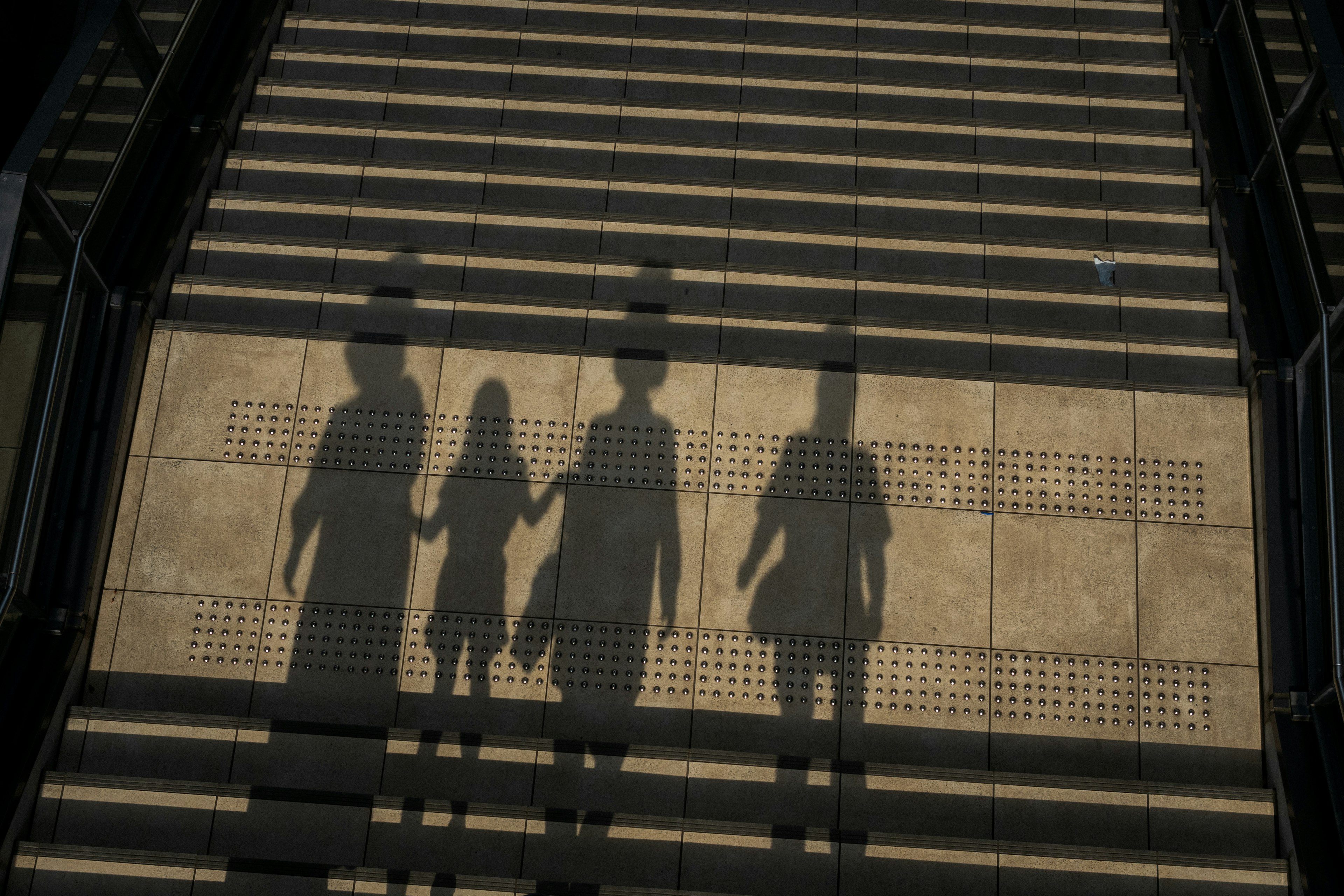 Drei Silhouetten, die sich an den Händen halten, während sie eine Treppe hinuntergehen