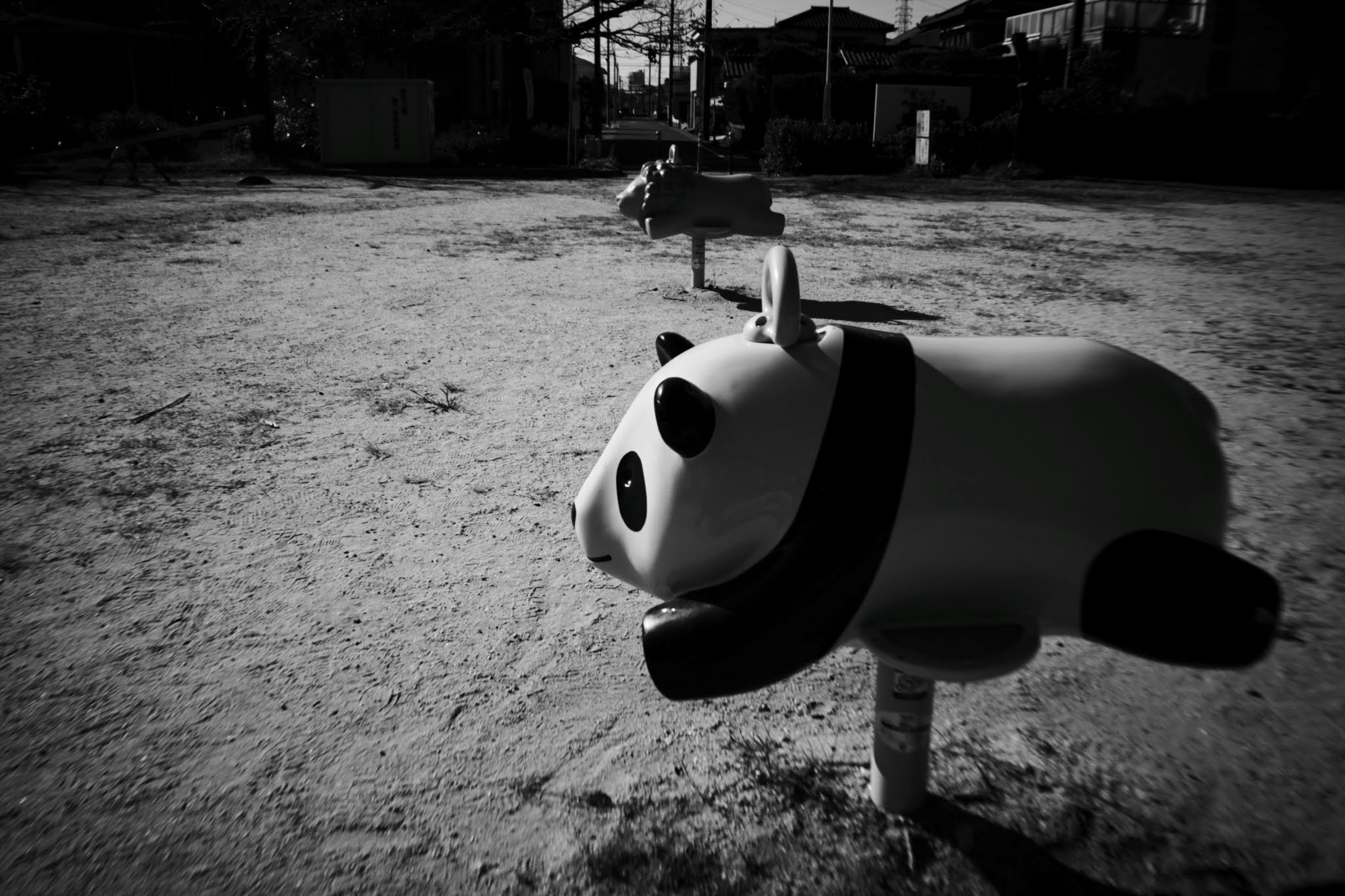 Un équipement de jeu panda se tient dans un parc avec un fond en noir et blanc