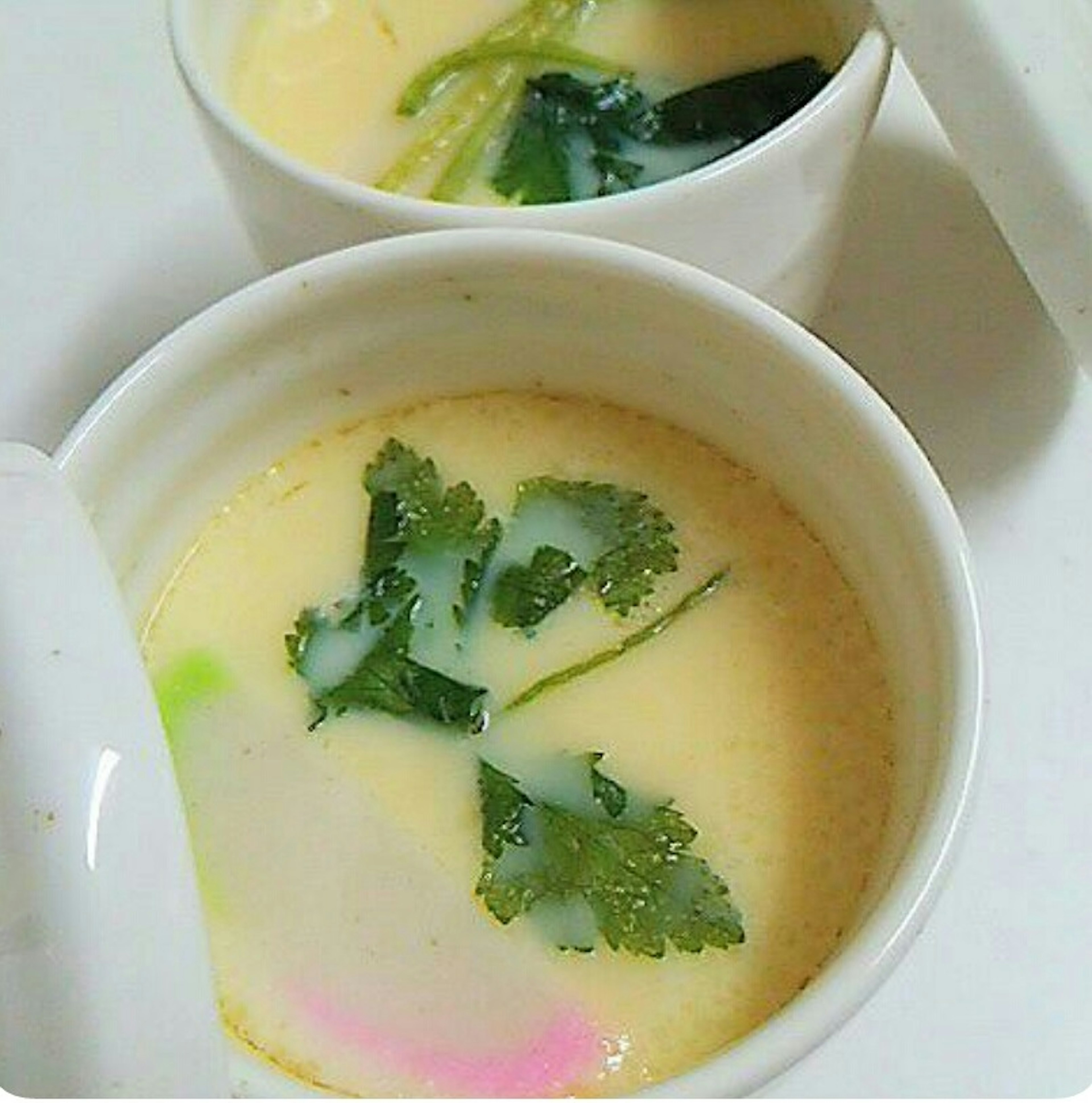 Chawanmushi servito in tazze bianche con verdure verdi e coriandolo