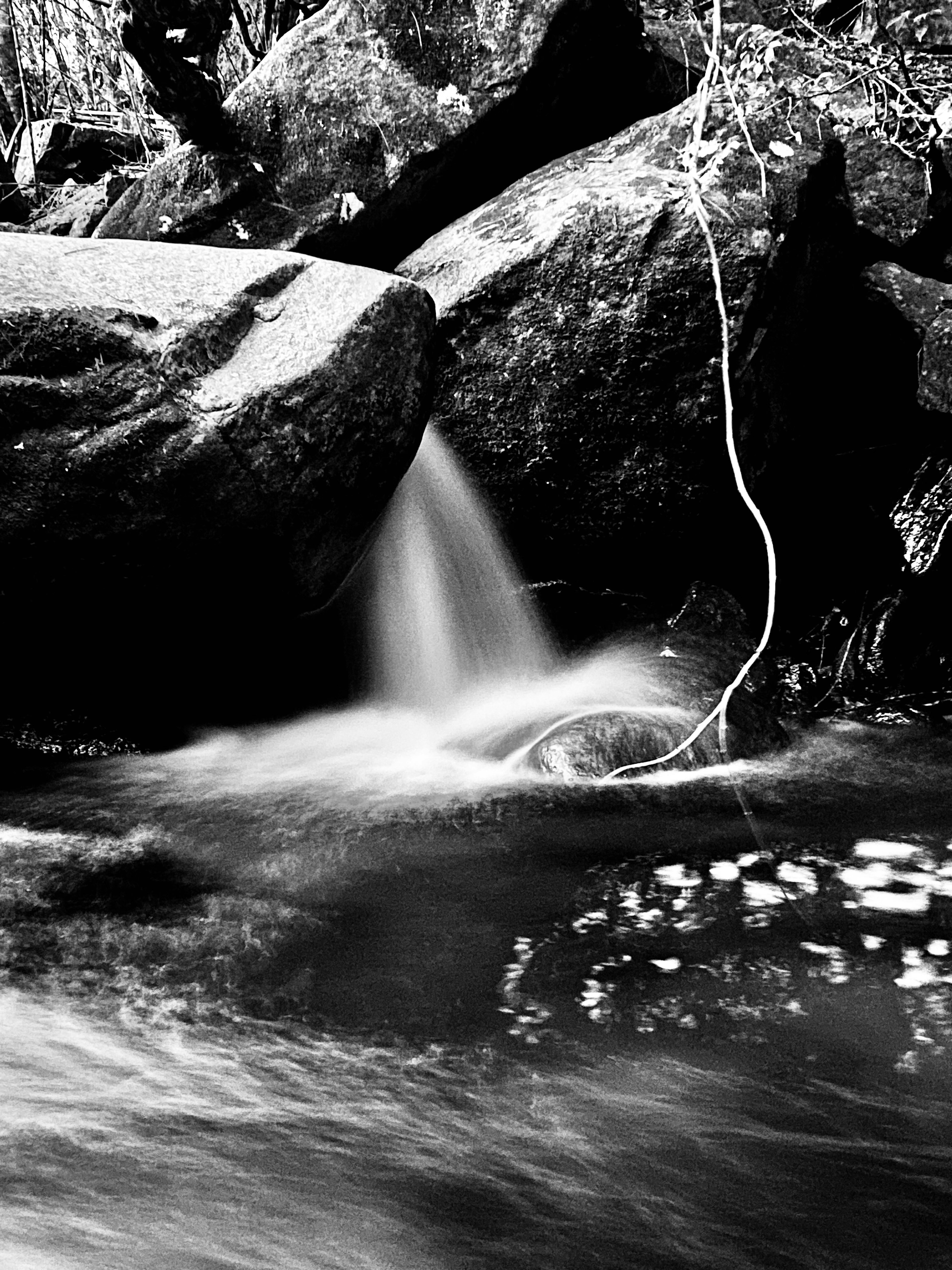 Black and white scene of flowing water and large rocks in a stream