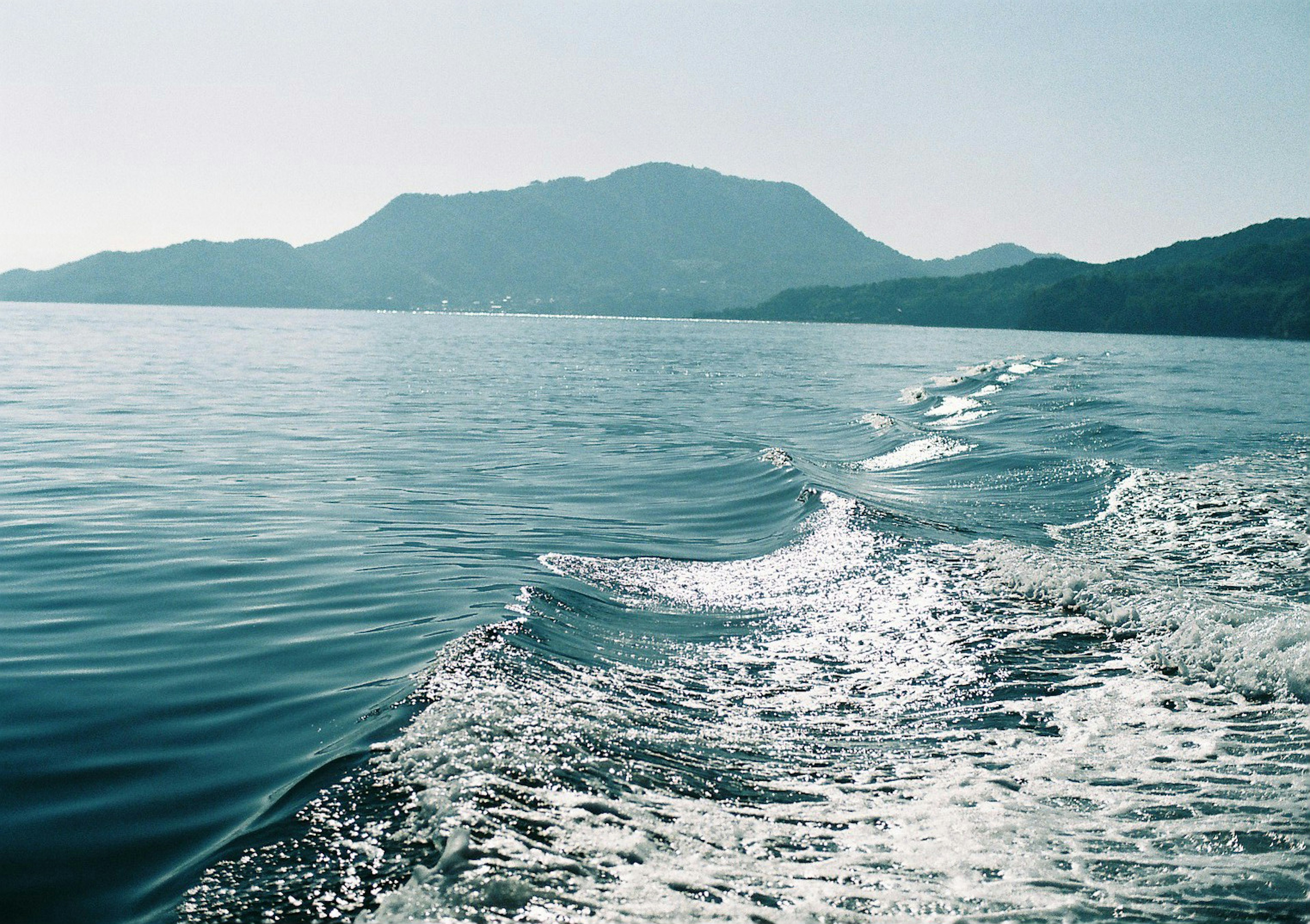 Pemandangan laut tenang dengan siluet gunung