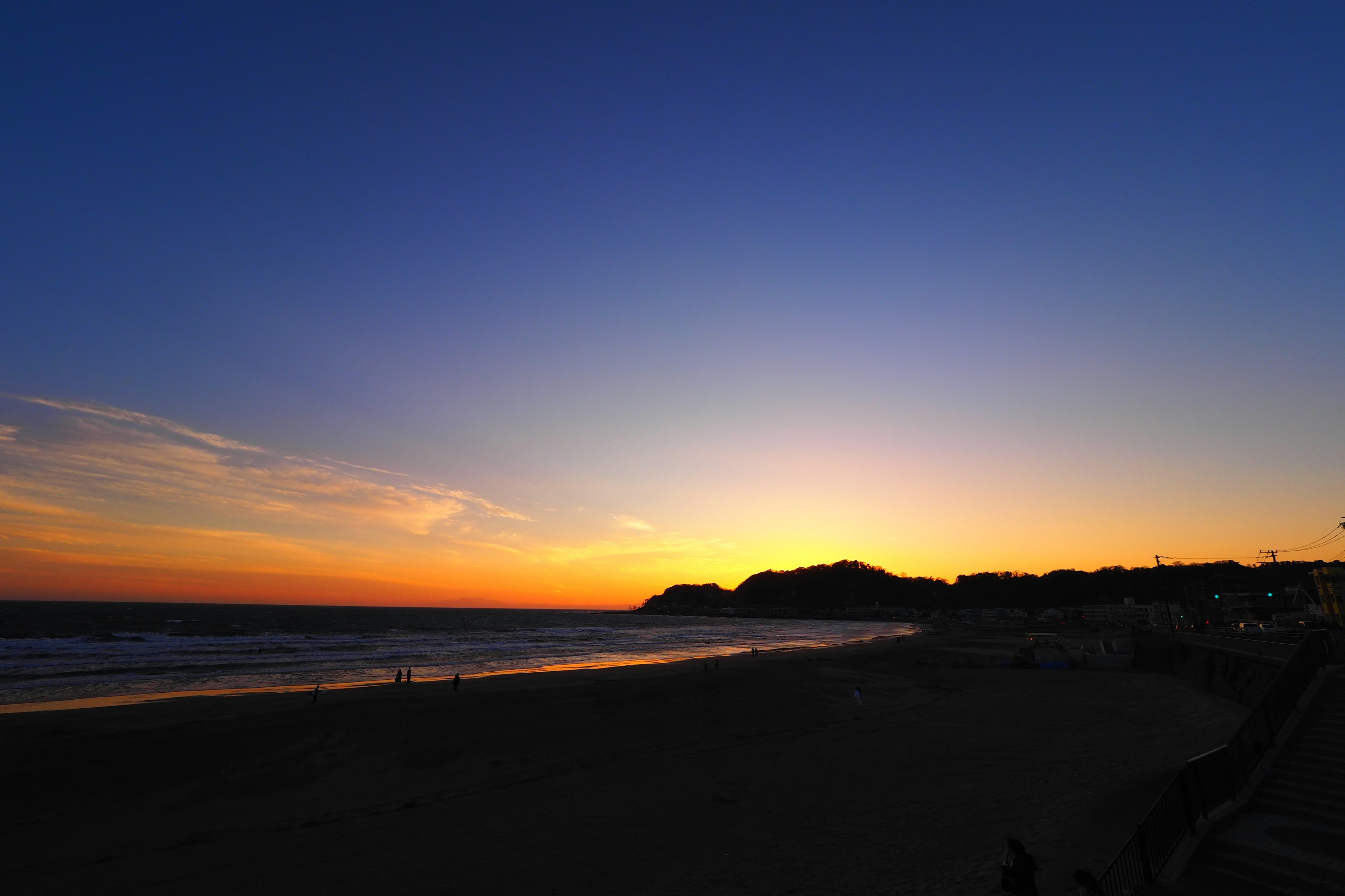 Vista de atardecer costero con cielo azul y naranja