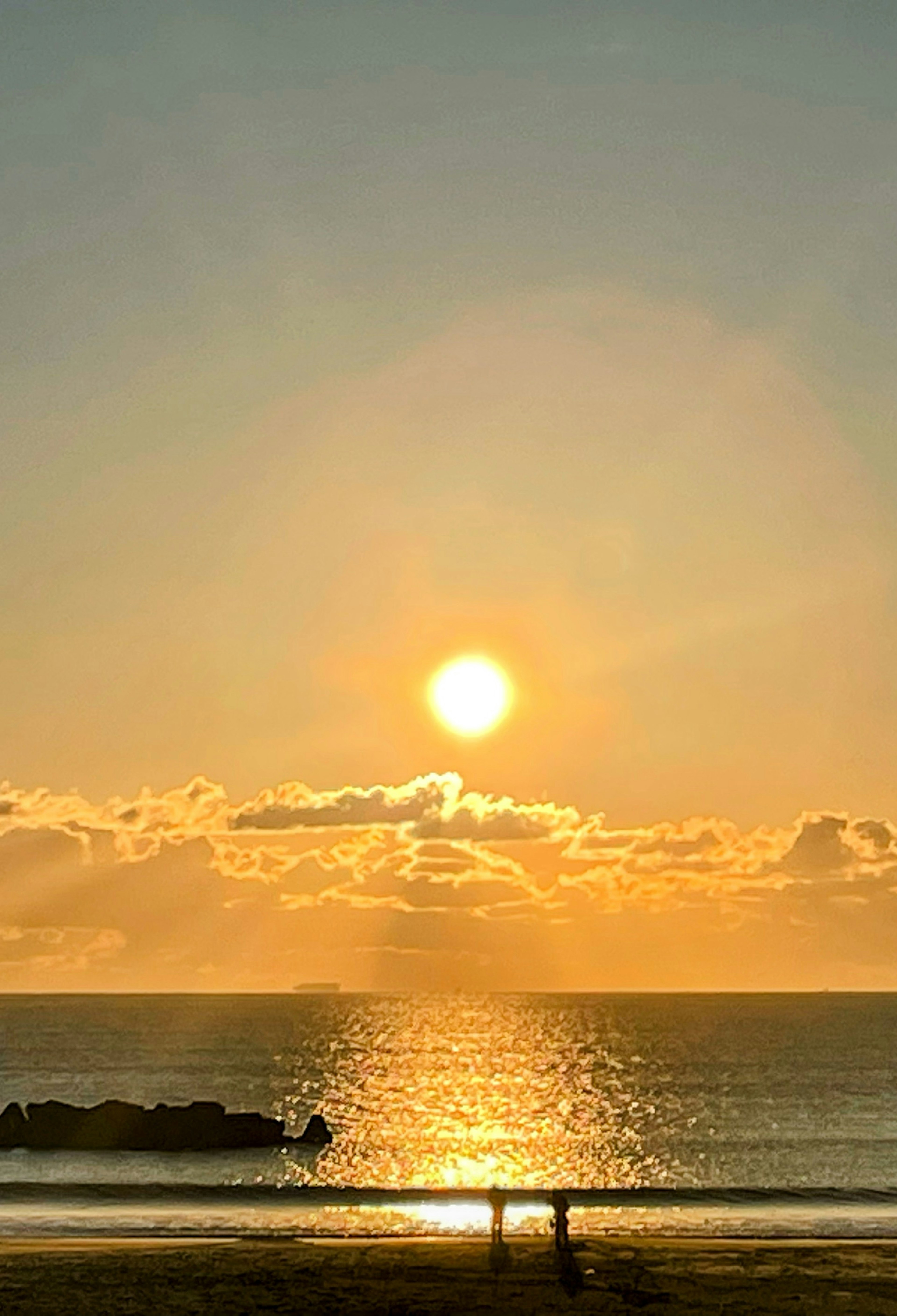 Hermoso atardecer reflejándose en el océano con siluetas de personas