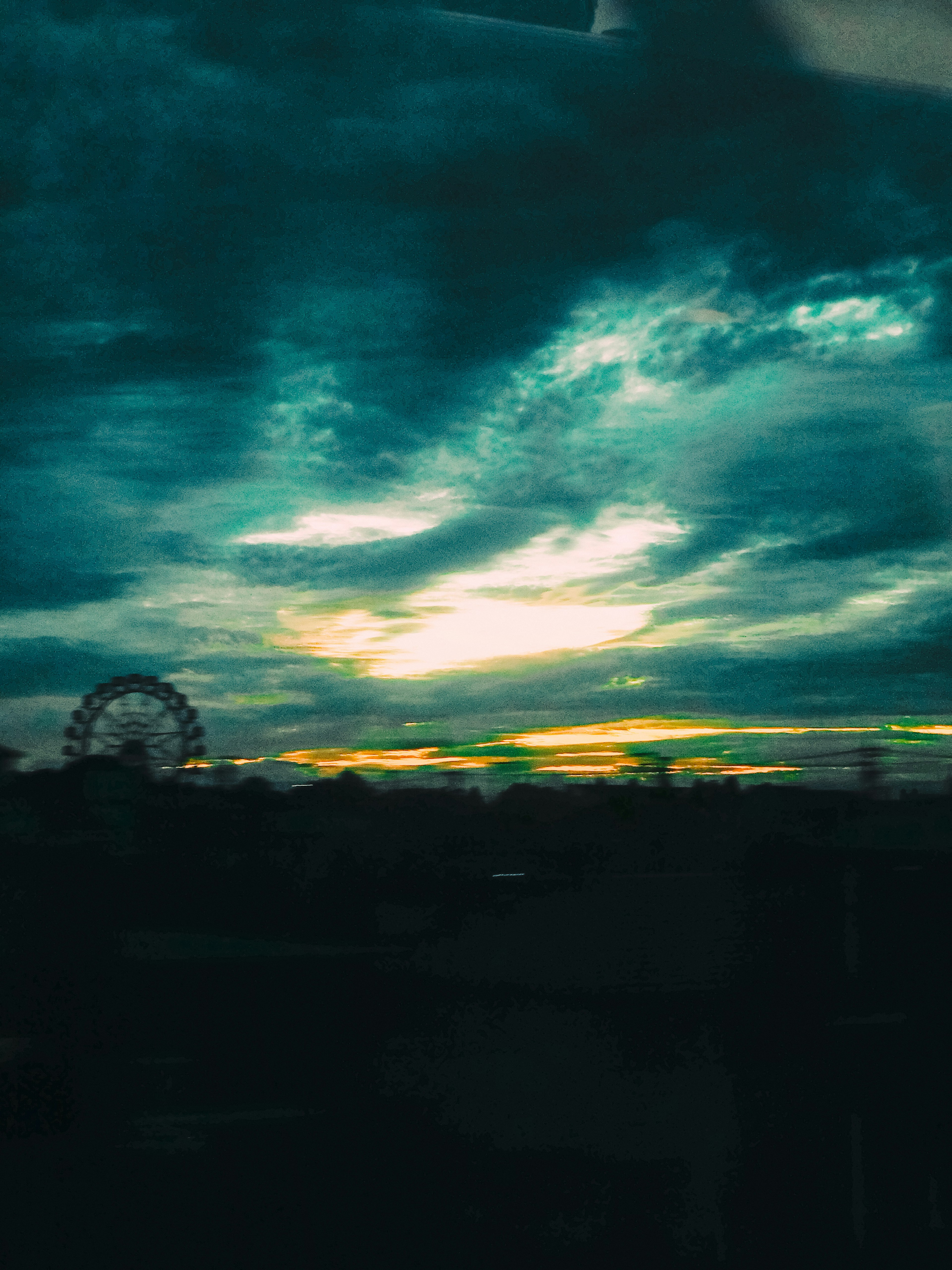 青い空と雲の下にある観覧車と夕焼けの風景