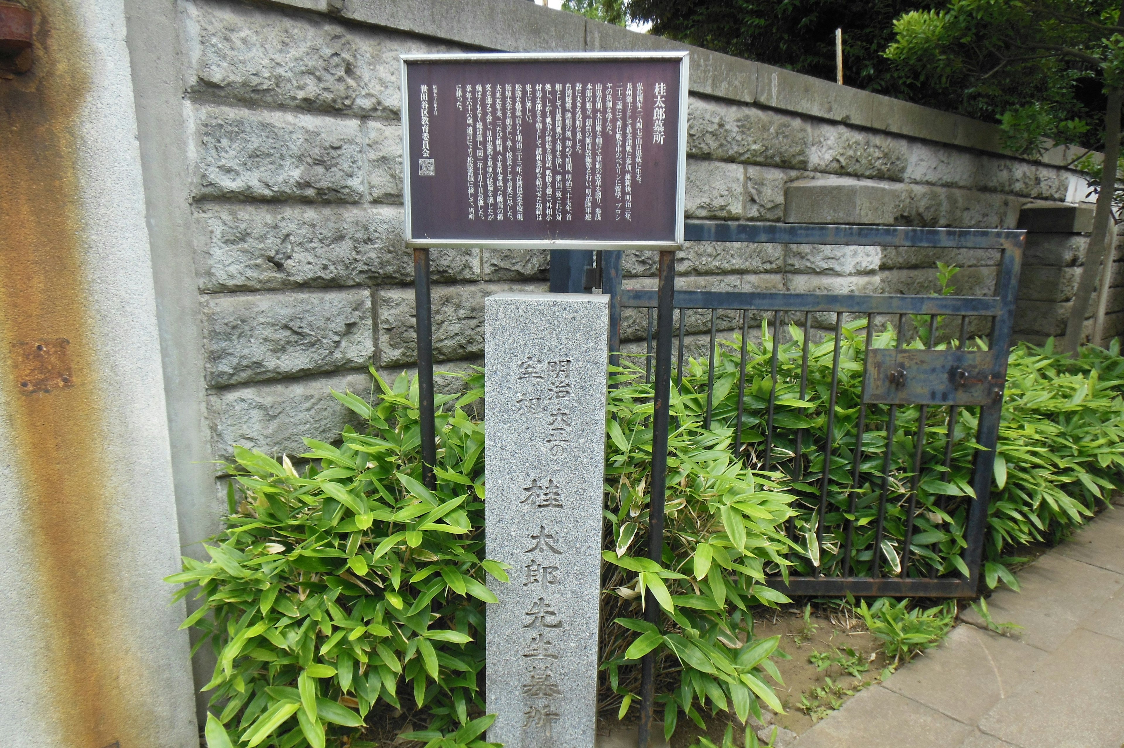 Gambar papan di depan tembok batu dan tanaman hijau