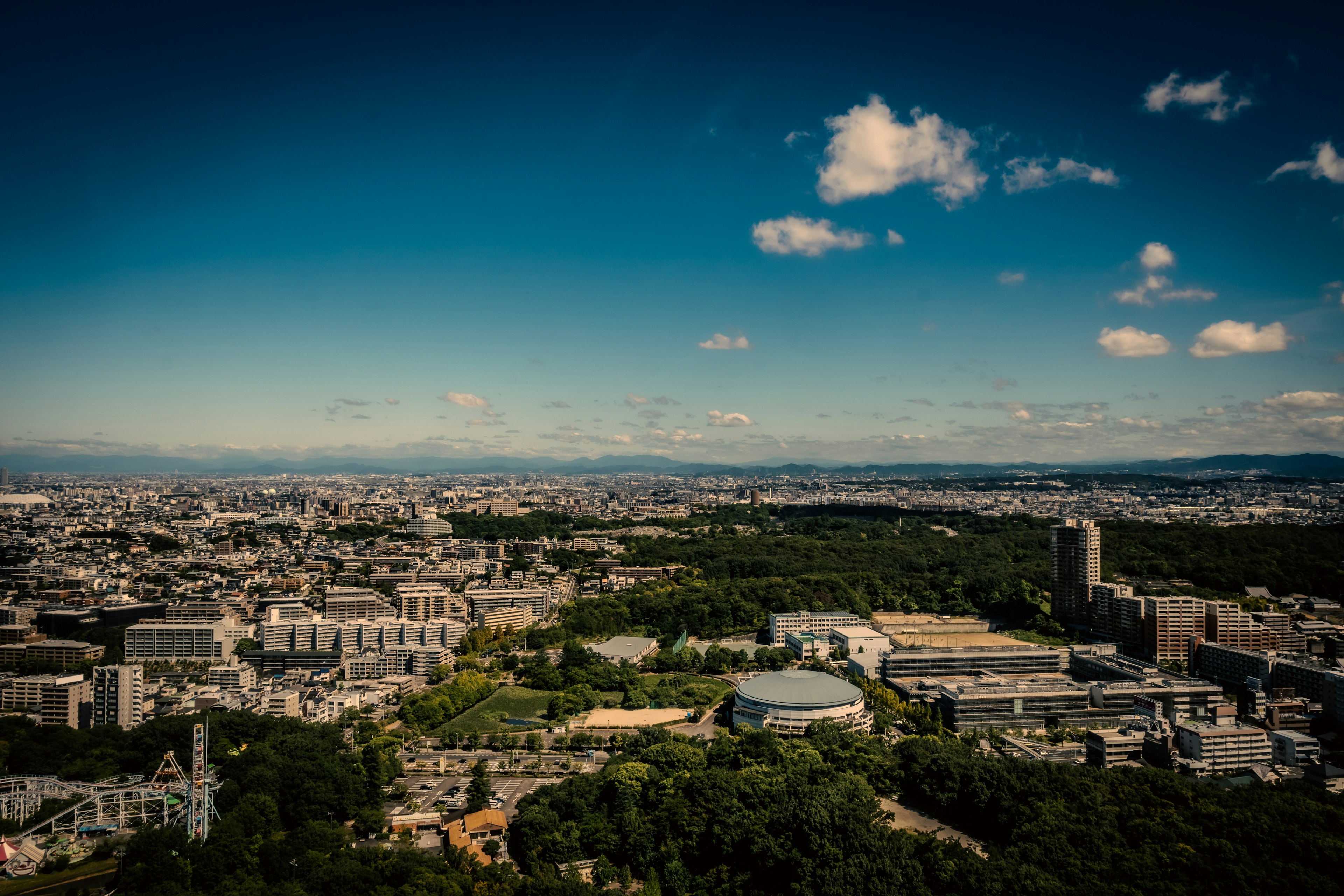 Vista panorámica de una ciudad bajo un cielo azul con parques verdes y edificios