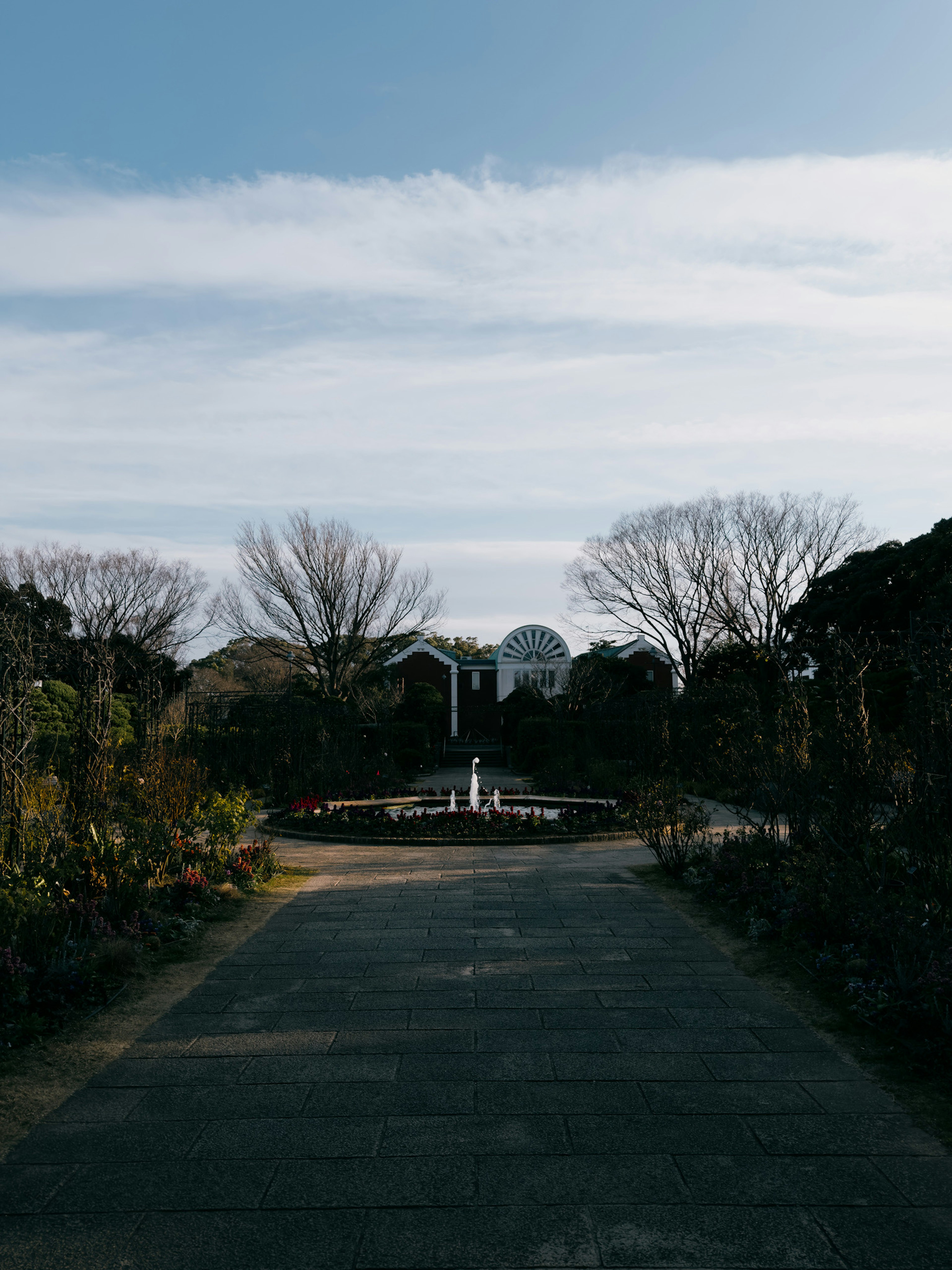 静かな公園の通路と後方の噴水と木々