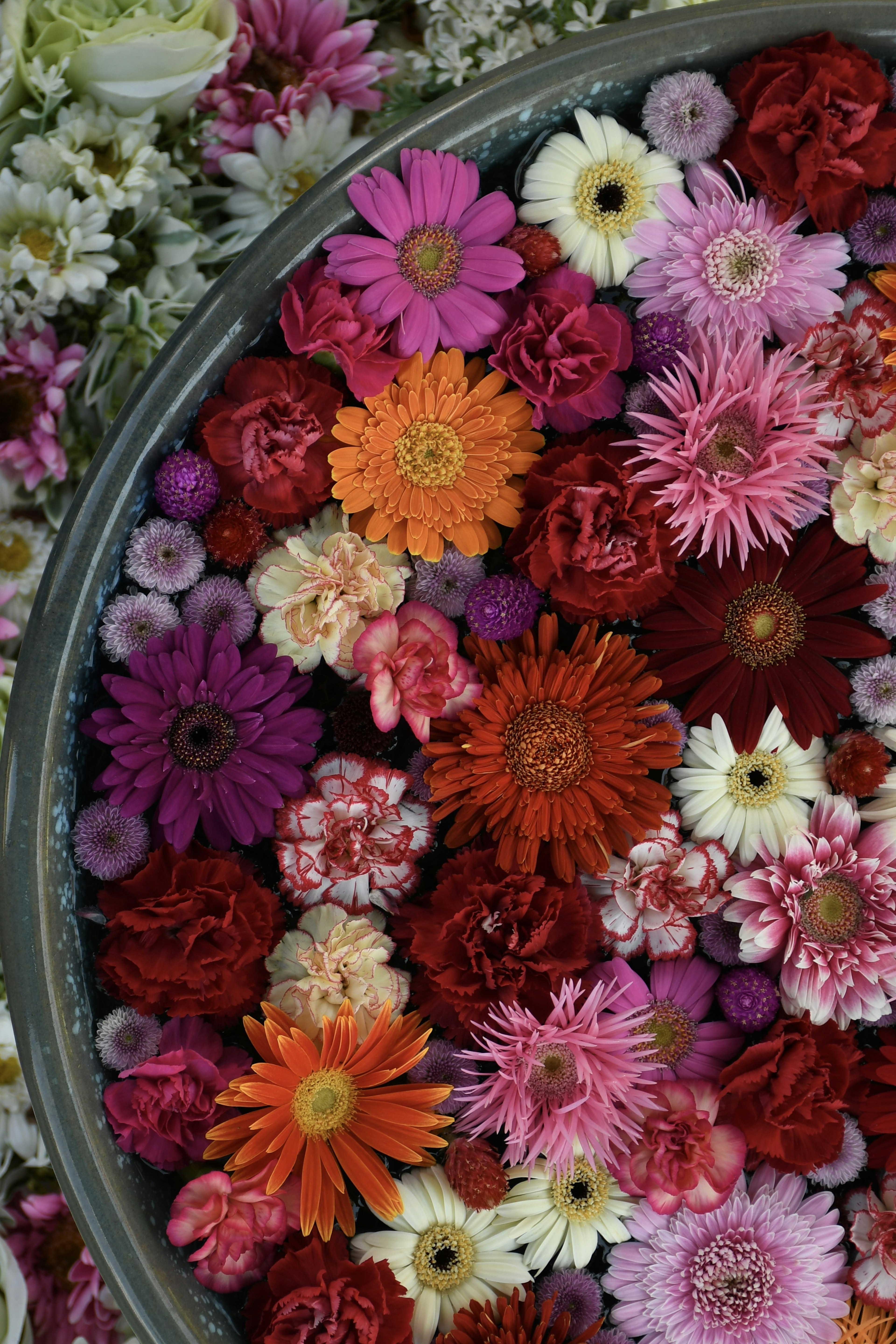 A large bowl filled with colorful flowers including gerbera daisies and carnations