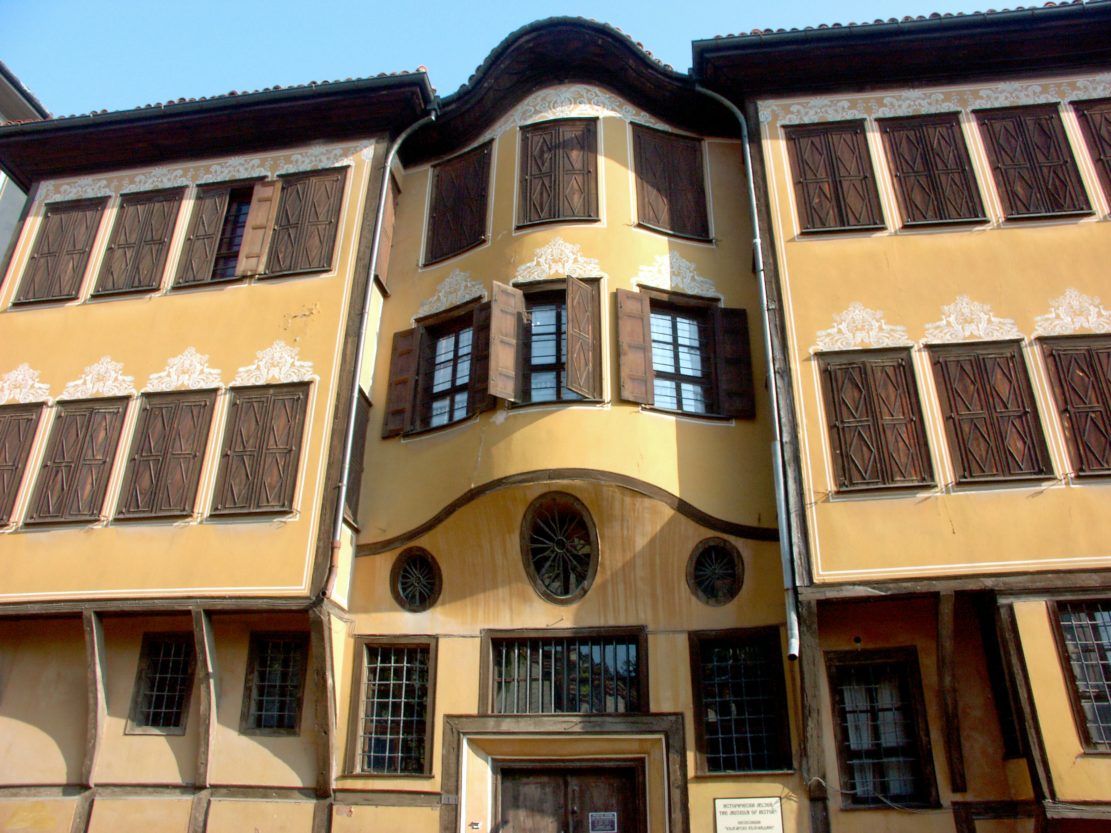 Facade of a historic building with decorative windows and yellow exterior