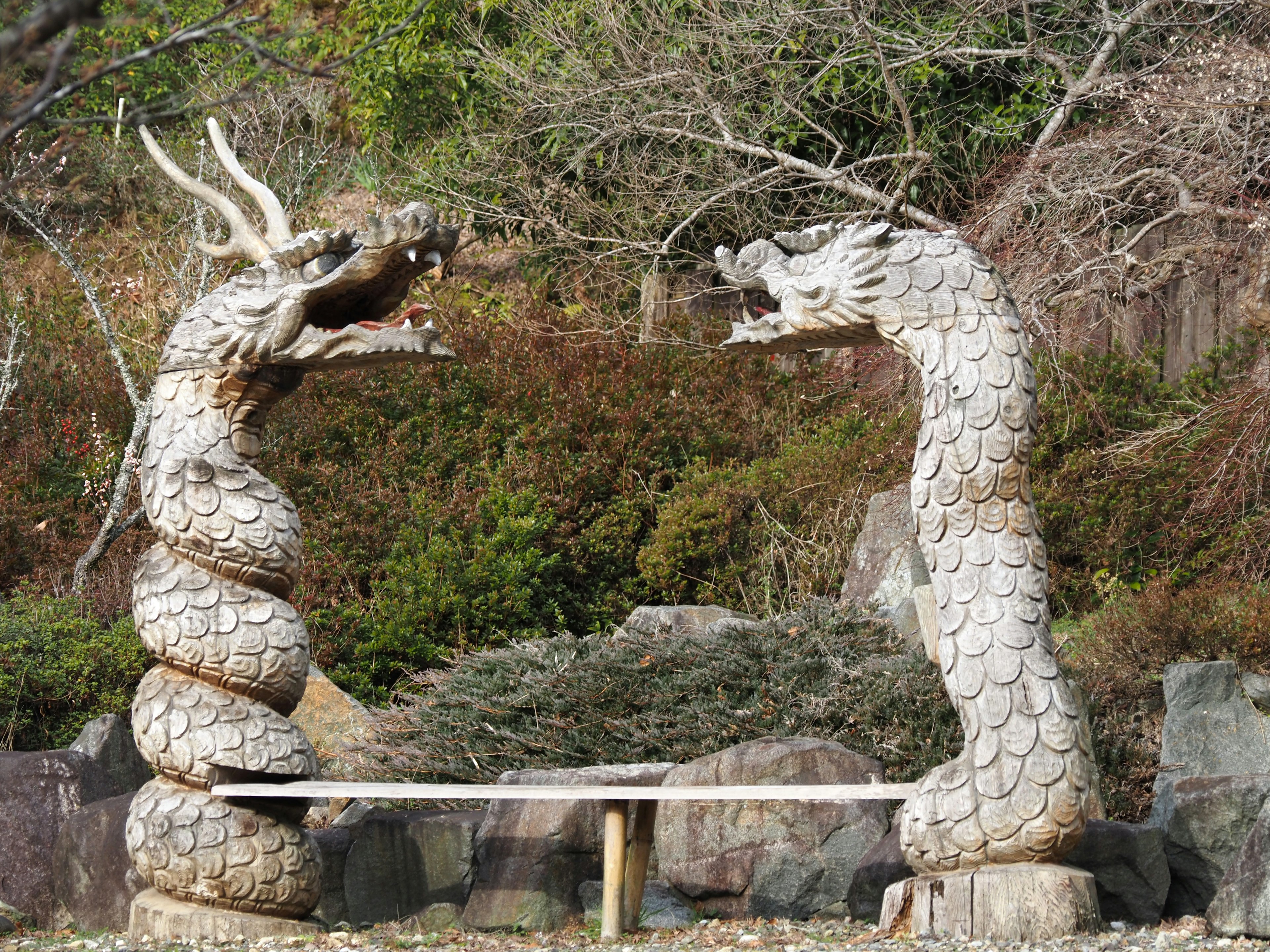 Deux sculptures de dragons se faisant face dans un cadre naturel