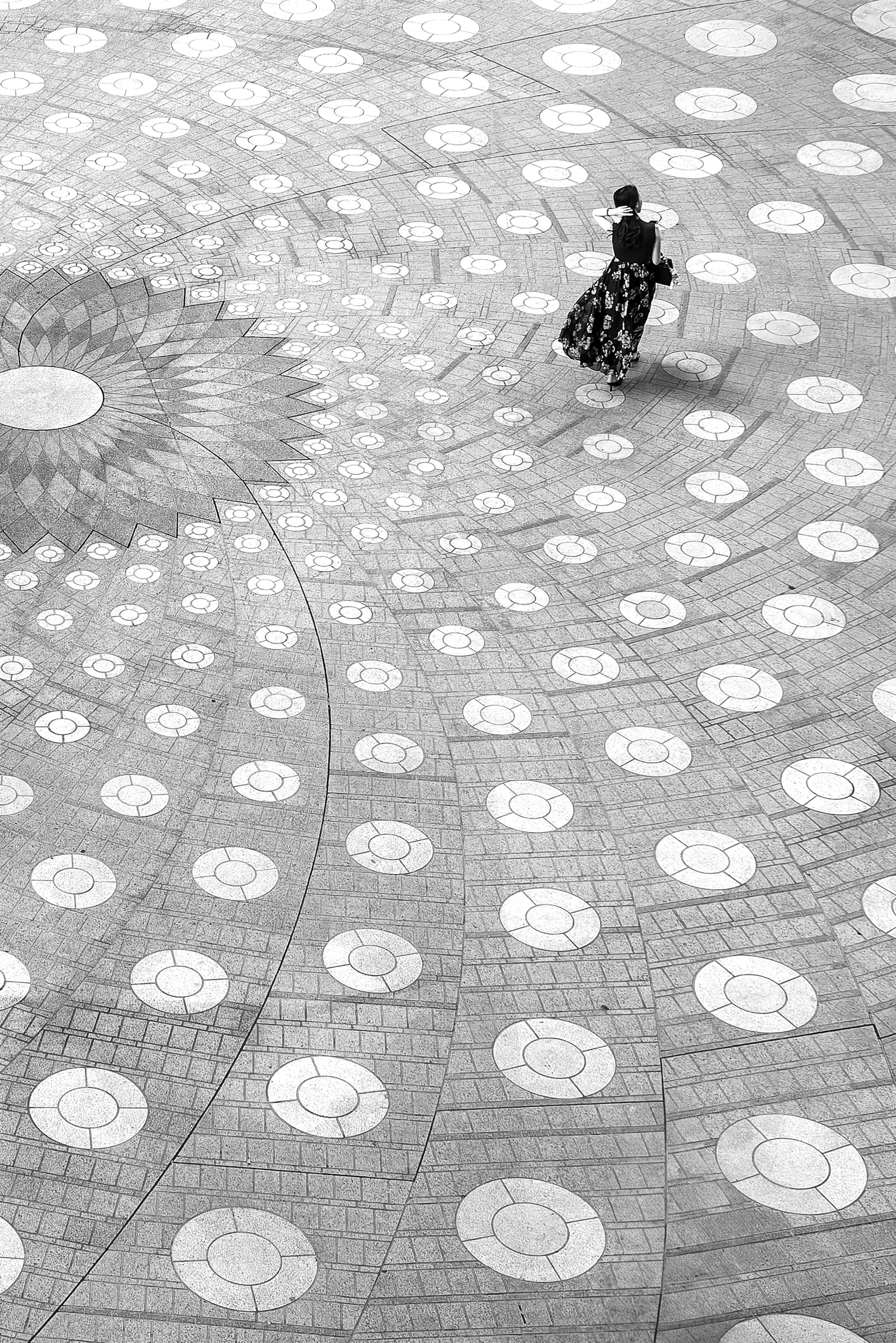 A person sitting on a patterned floor with circular designs from a top-down perspective