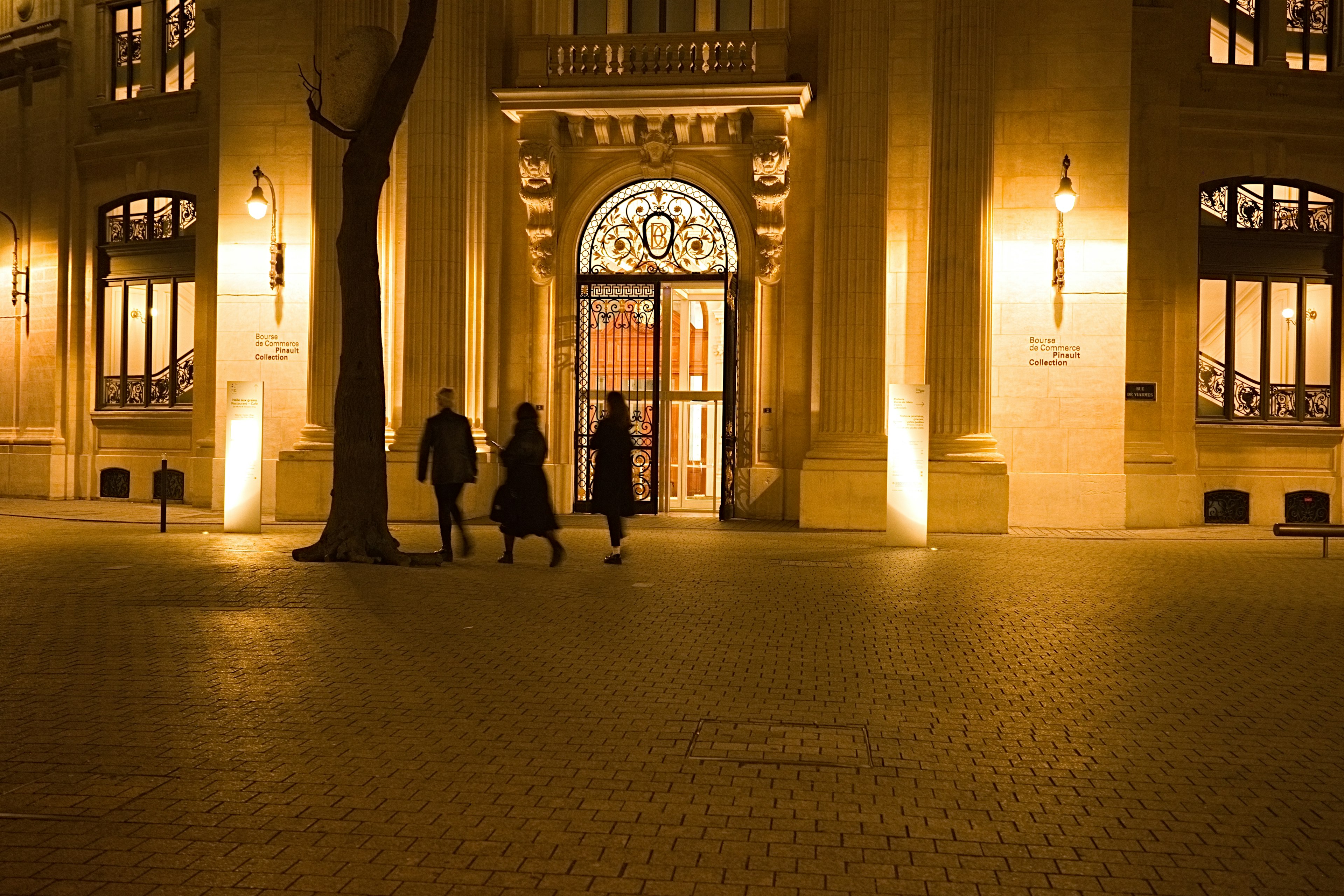 Personas caminando de noche frente a un edificio histórico